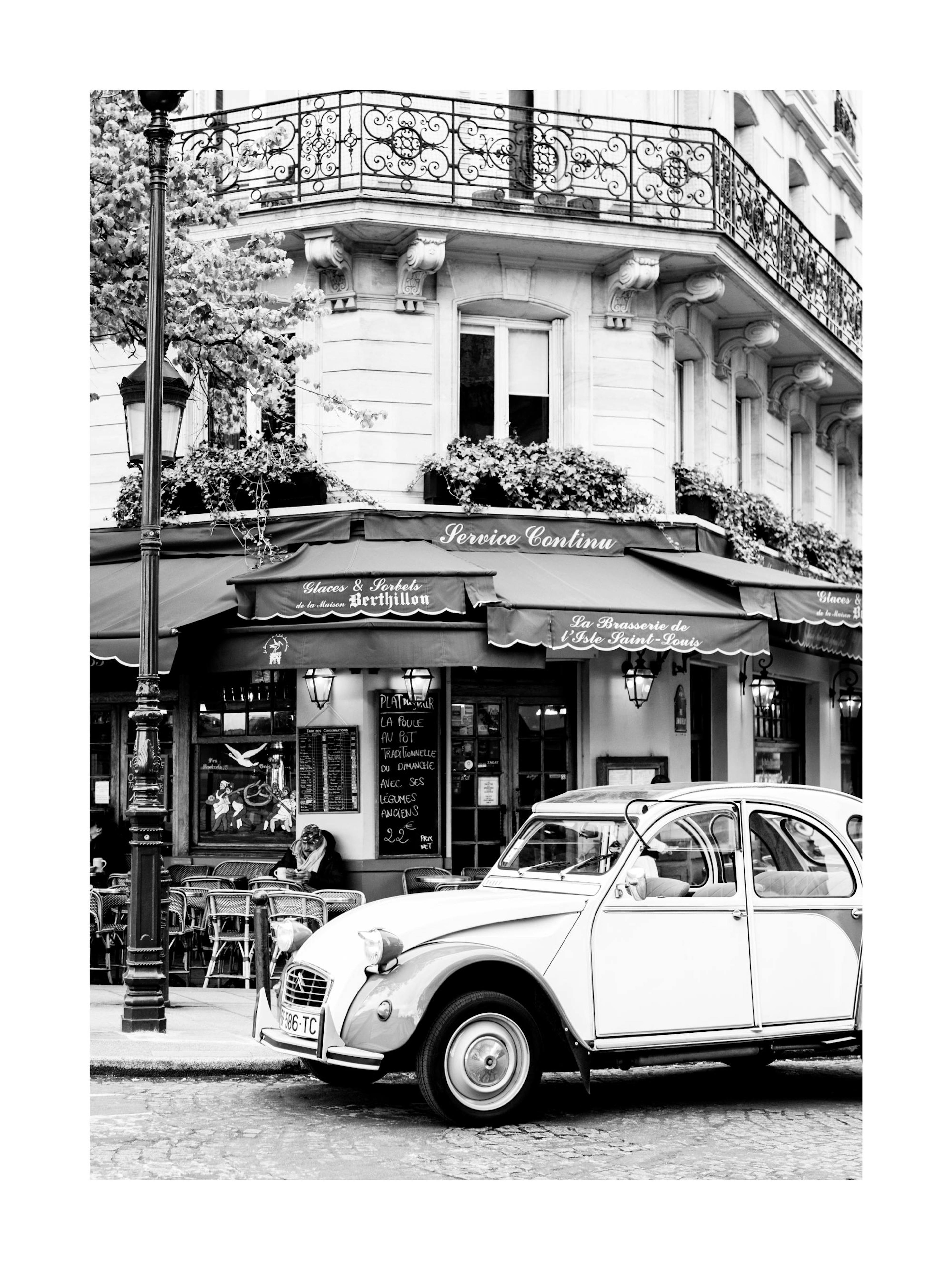 Black and white poster of a classic car parked in front of a Parisian cafe with outdoor seating.