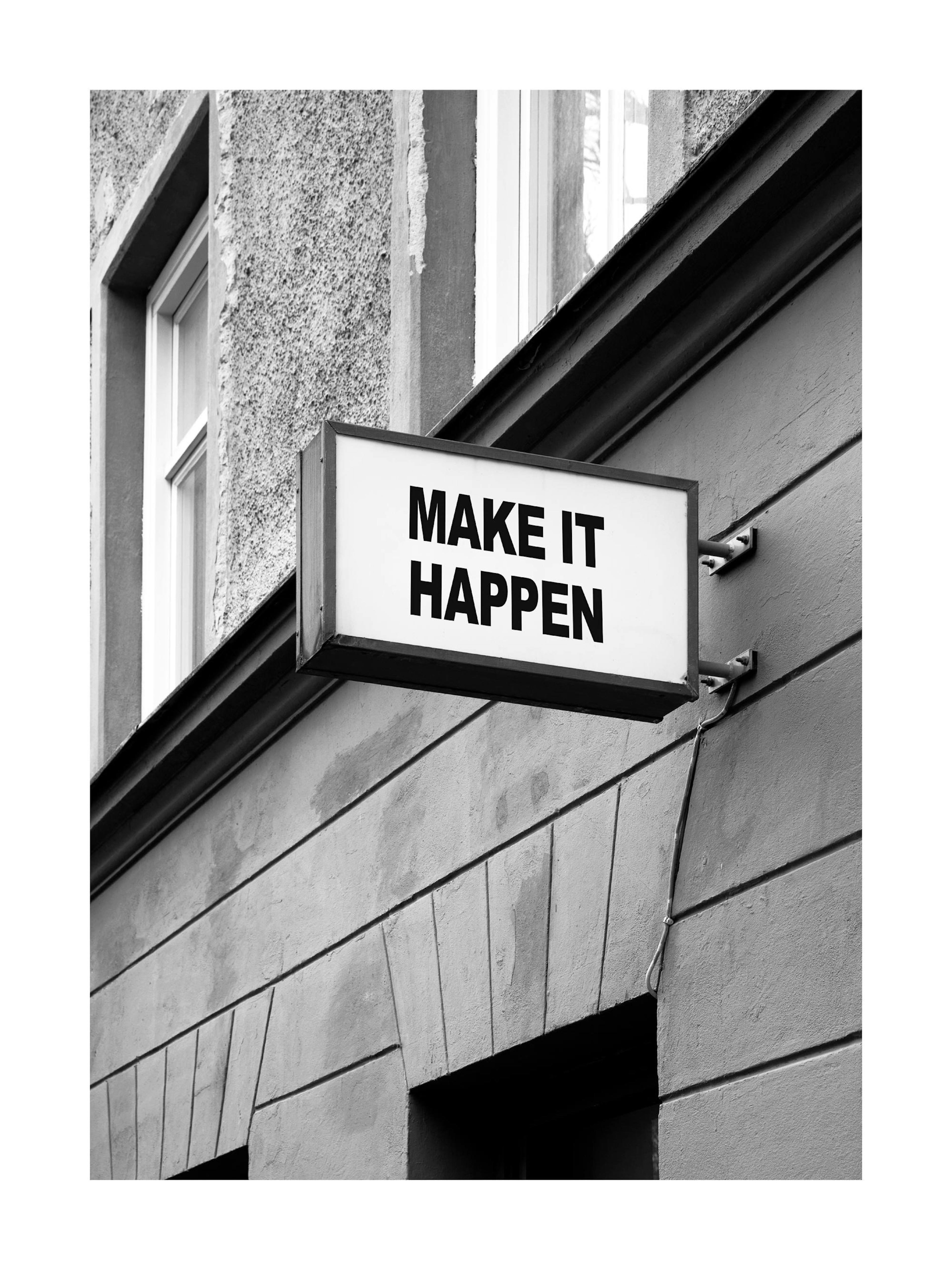 Póster en blanco y negro de un letrero luminoso en un edificio que dice MAKE IT HAPPEN.