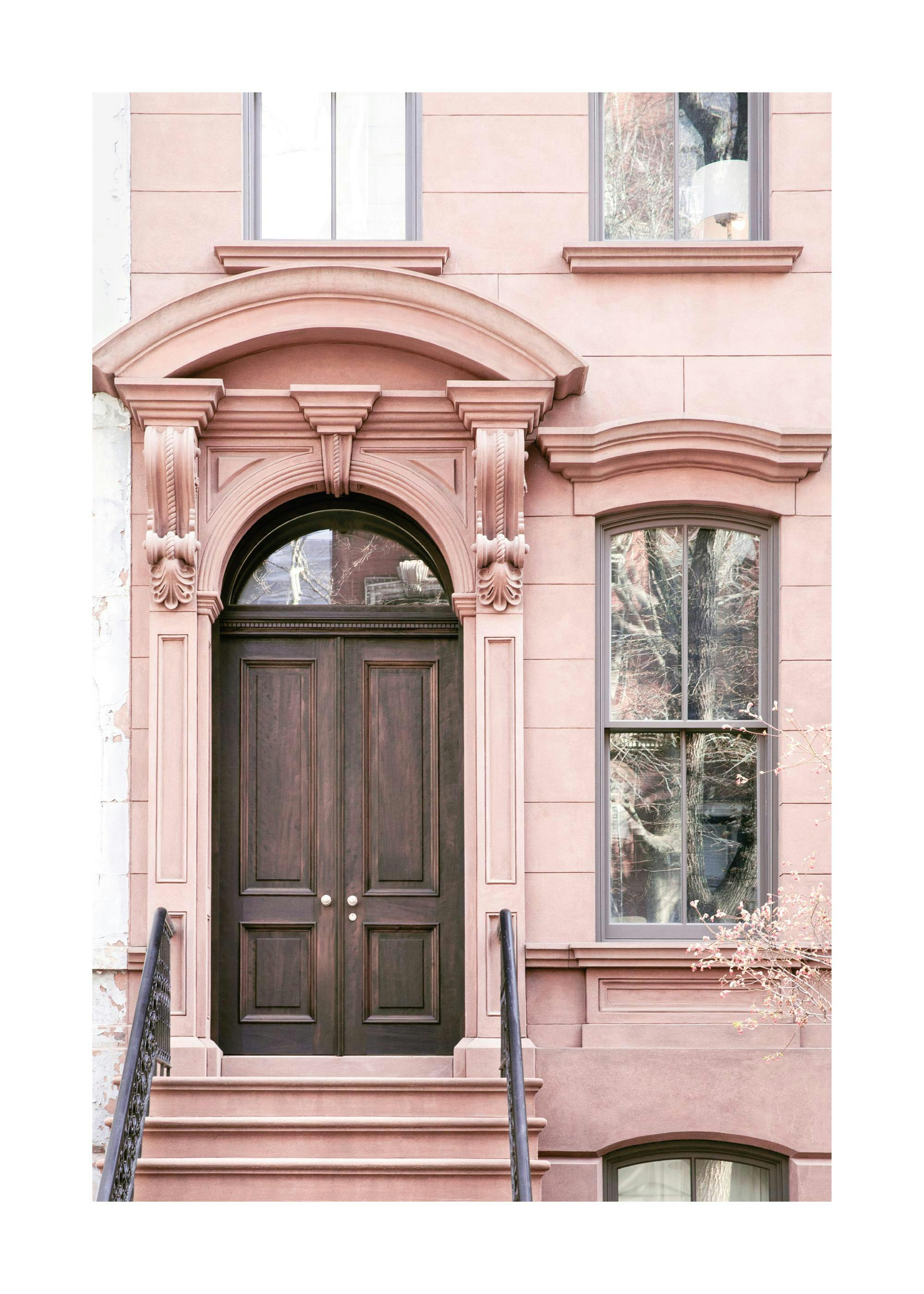 Poster dune façade de maison rose pâle avec une porte dentrée en bois foncé, des fenêtres et des escaliers.