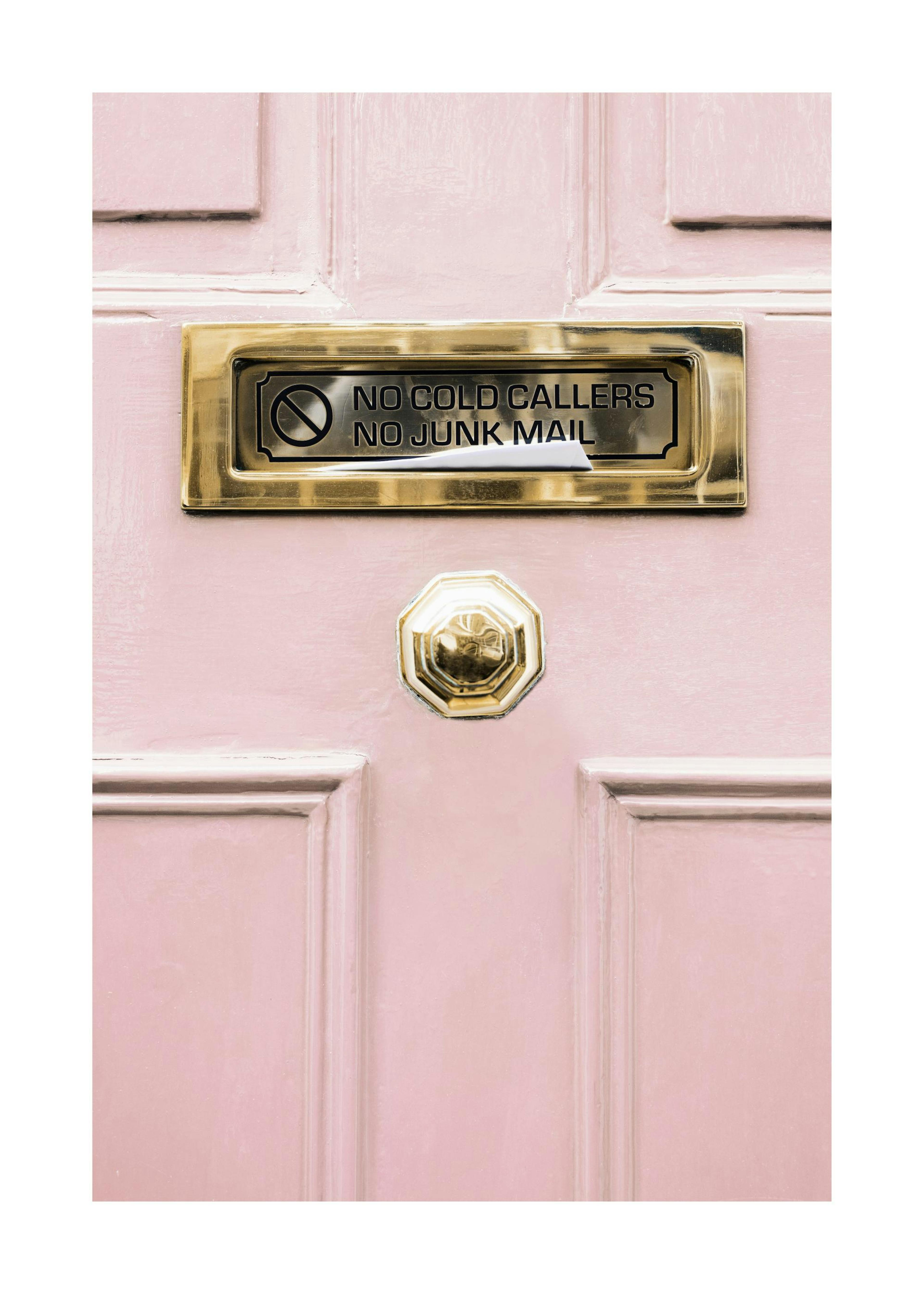 Póster de una puerta rosa con un buzón de latón, que dice NO COLD CALLERS NO JUNK MAIL.