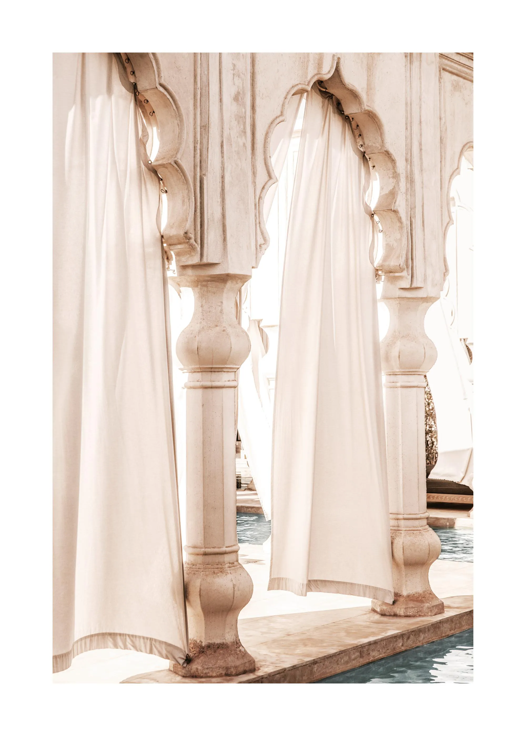 Poster con pilastri in pietra color sabbia e tende bianche che si affacciano su una piscina, stile resort.