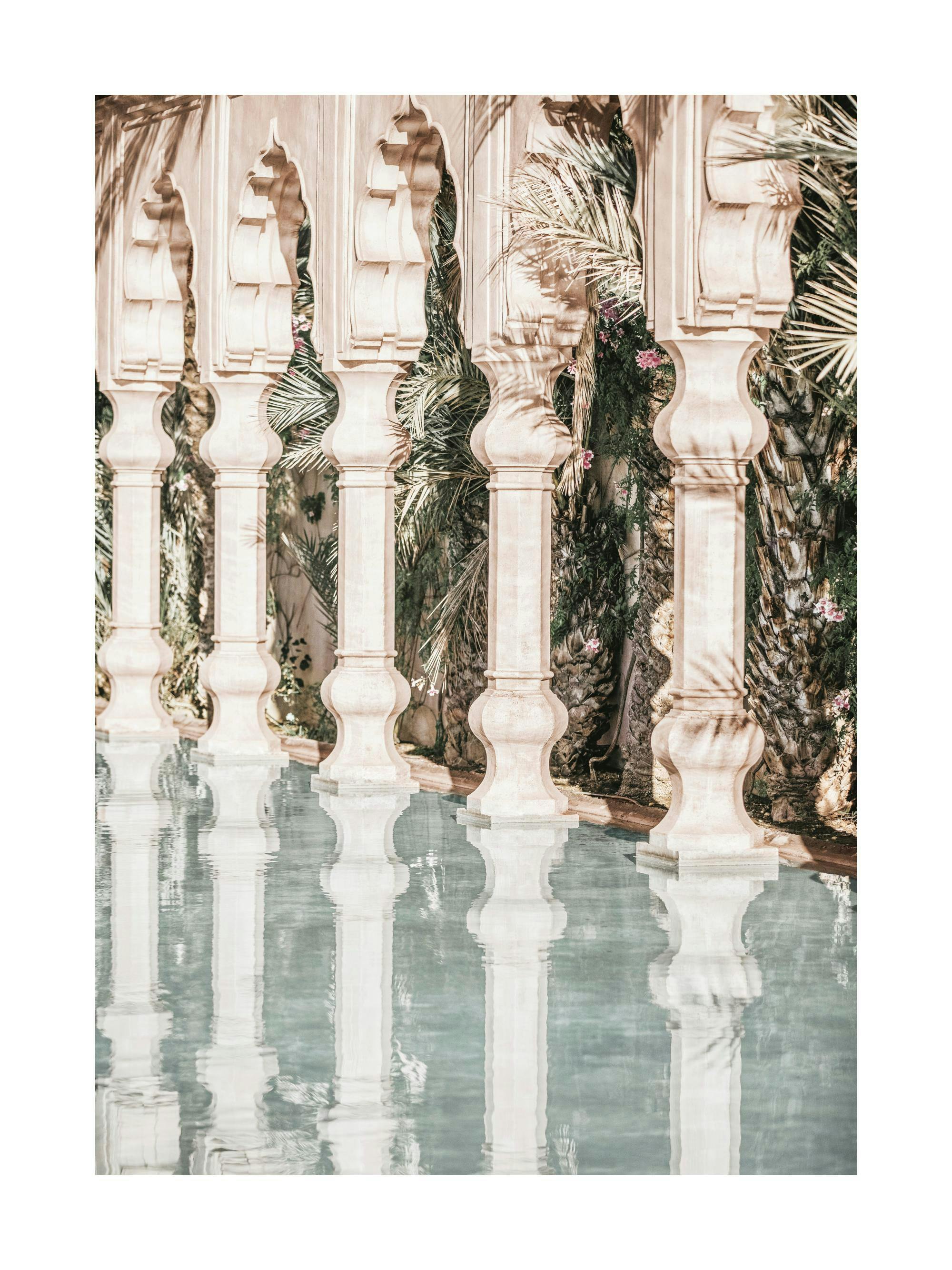 A poster featuring a row of arched, light-coloured columns reflected in still water, with palm trees and flowers in the backgrou
