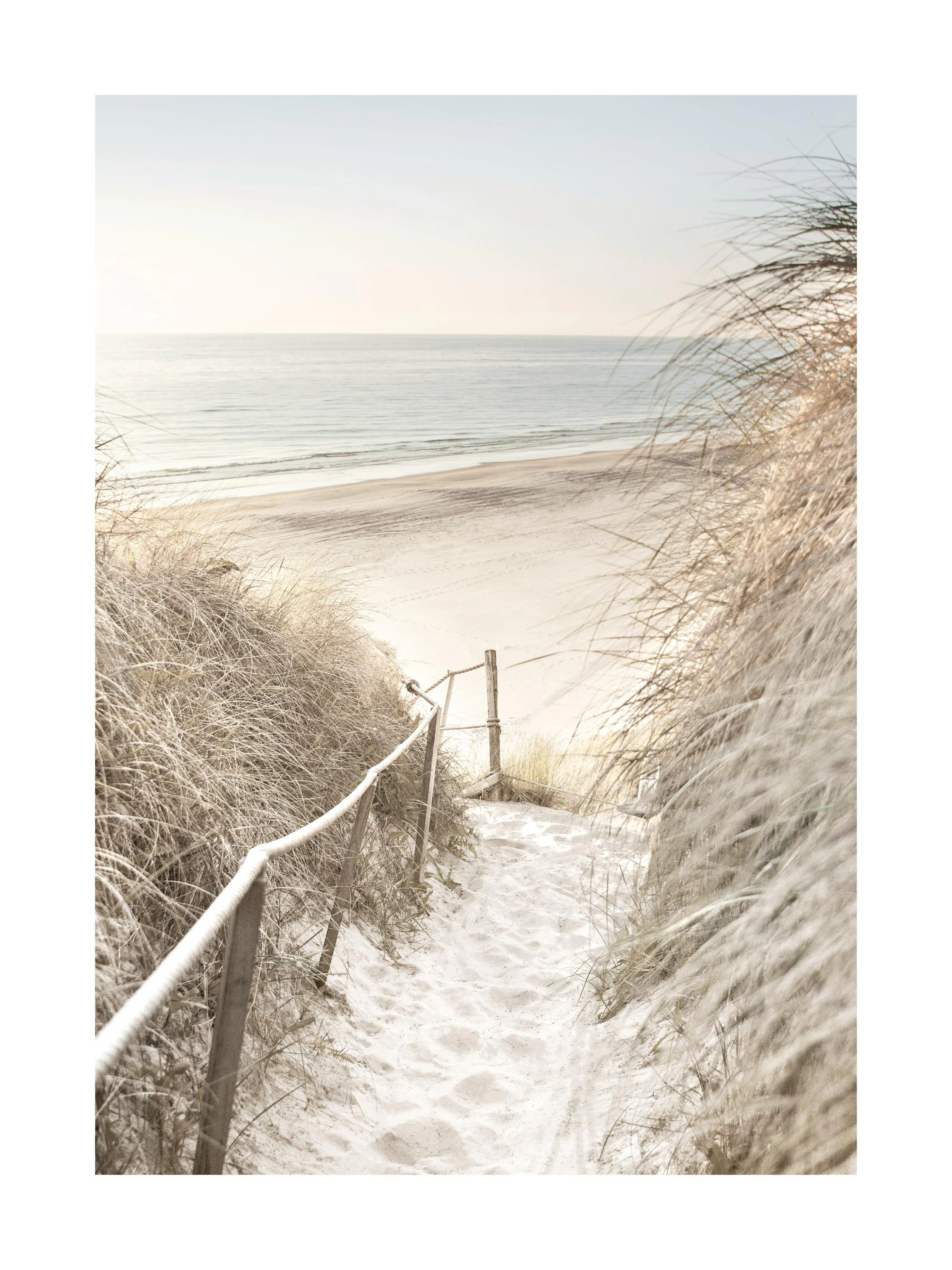 Plakat przedstawia piaszczystą ścieżkę prowadzącą przez wydmy na spokojną, słoneczną plażę.