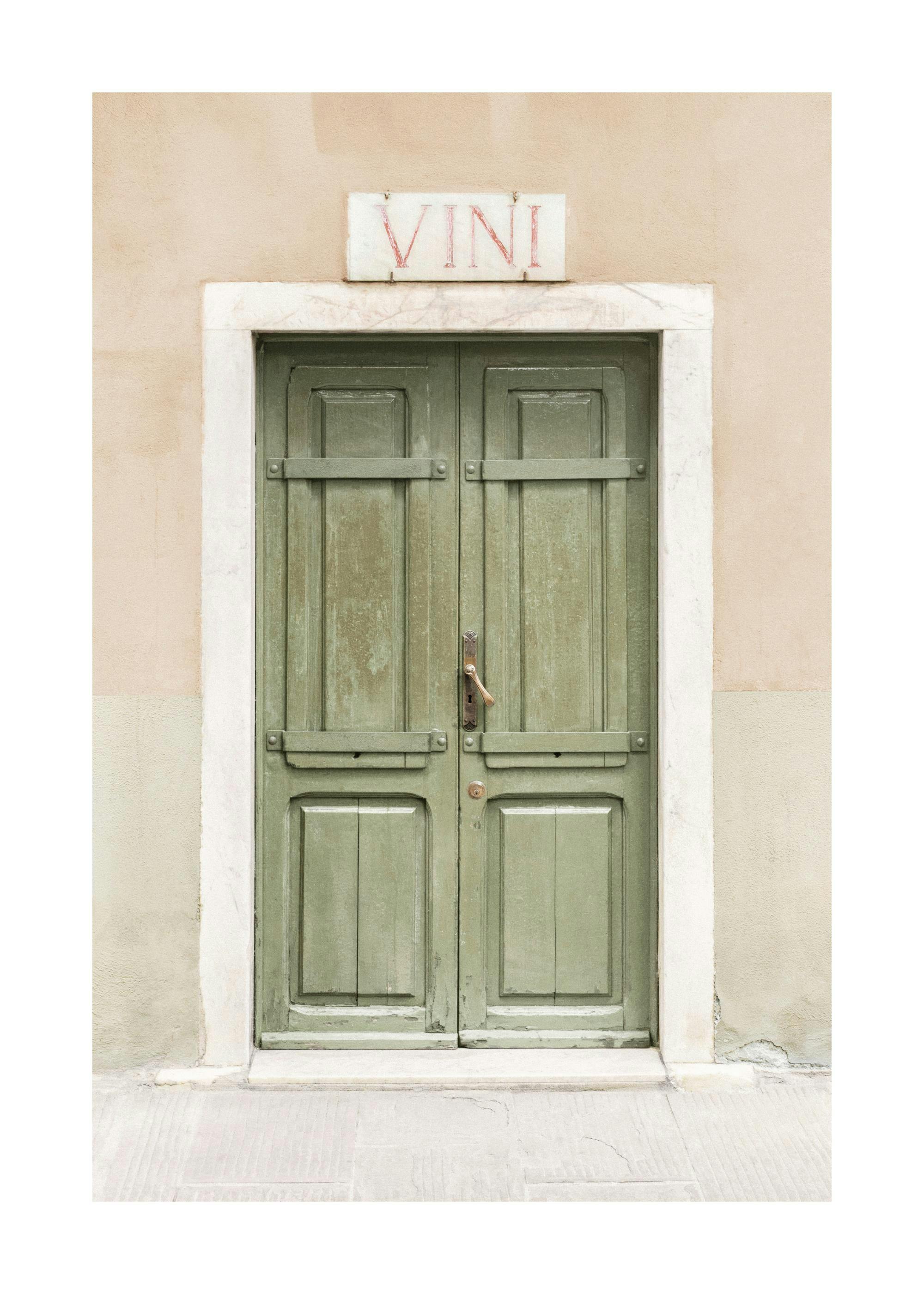 A poster featuring a weathered, light green wooden door with a brass handle, set in a light beige stucco wall with a white stone