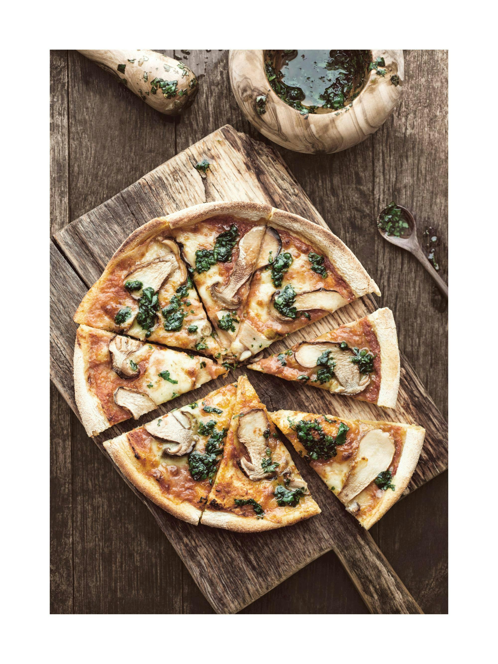 A poster featuring a delicious mushroom and spinach pizza on a wooden board, with a mortar and pestle of herbs.