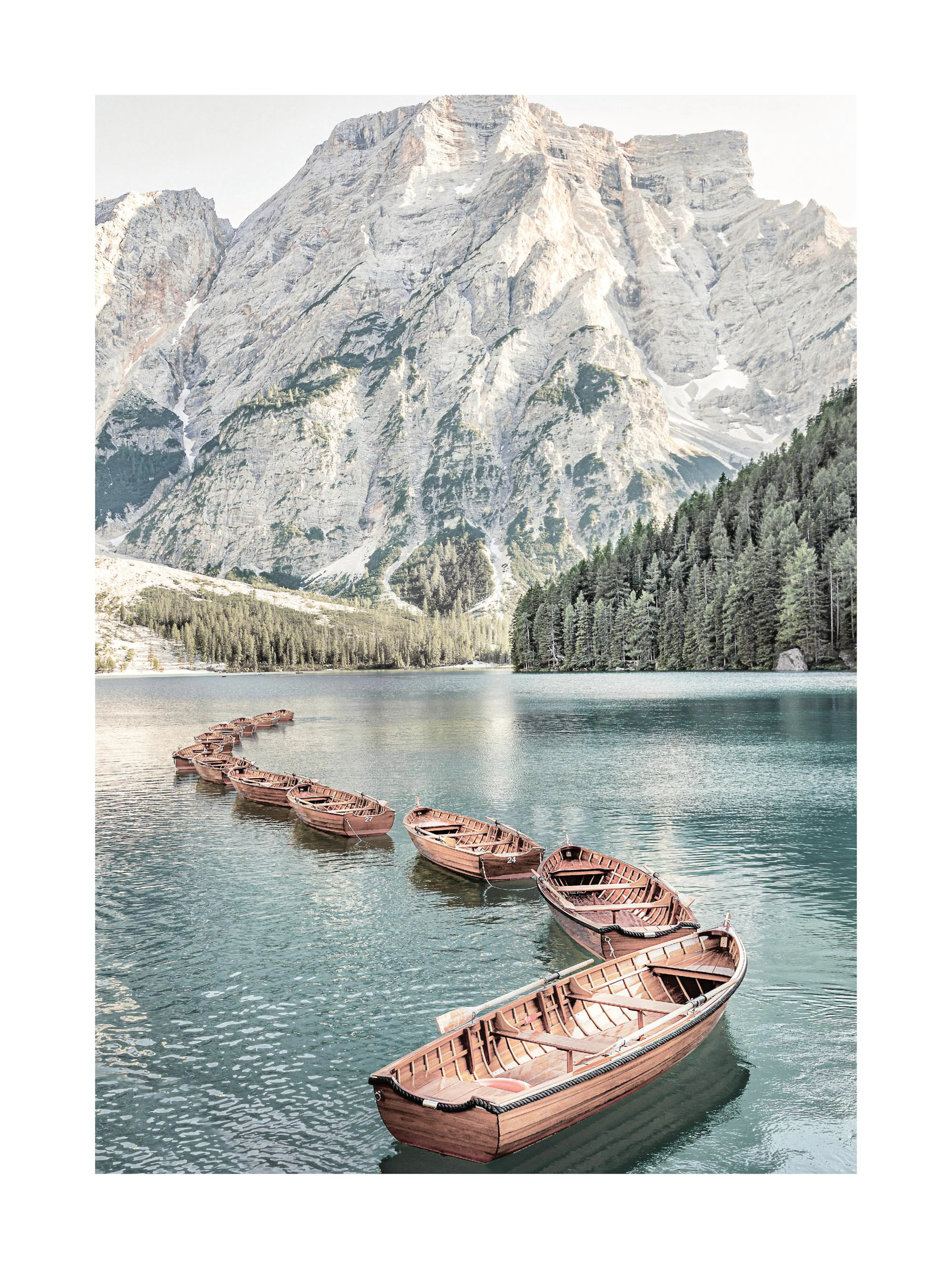 A poster featuring wooden rowboats floating on a lake with mountains and pine trees in the background.