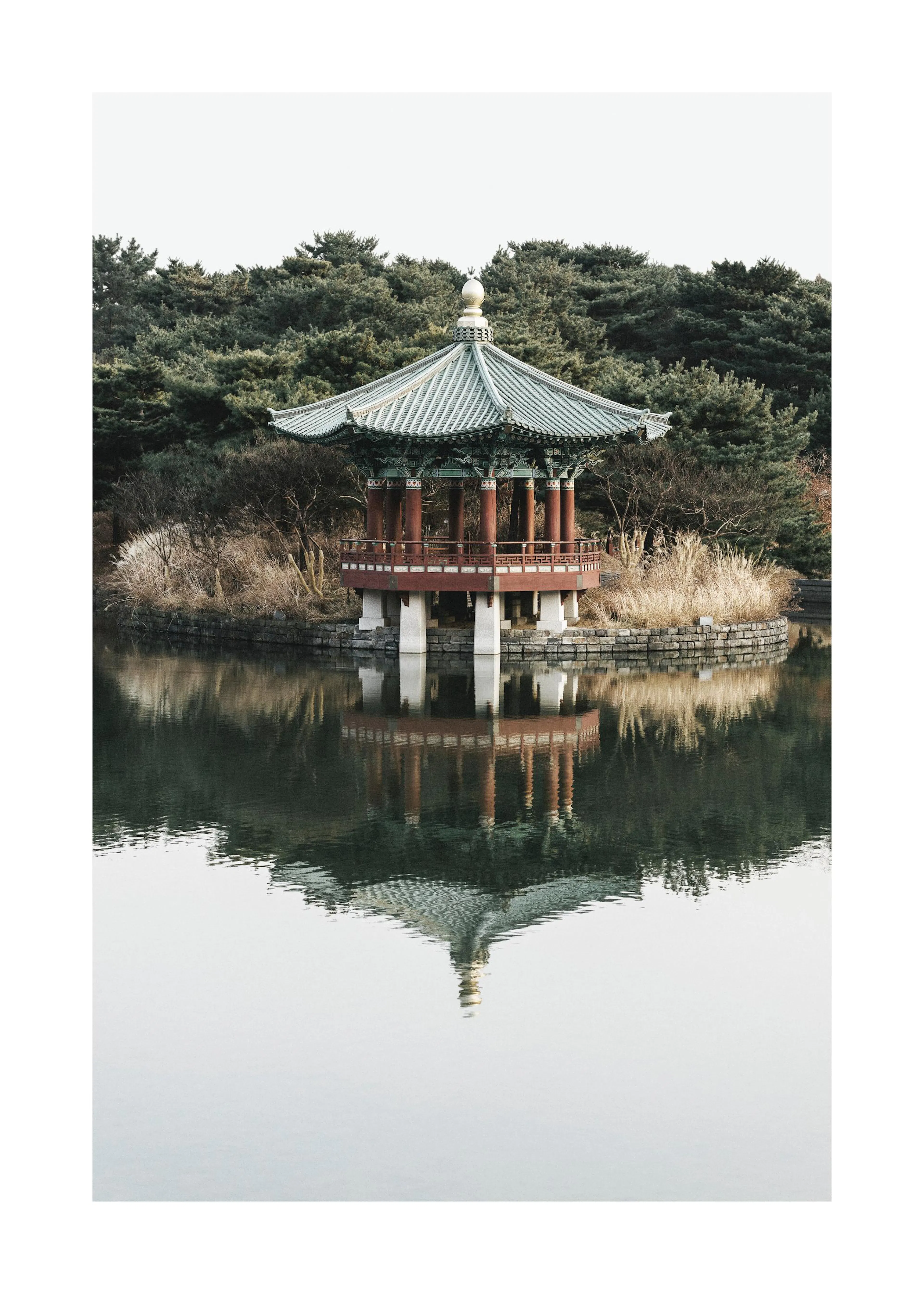 Een poster van een traditionele Koreaanse pagode op een eiland in een serene vijver met weerspiegeling.