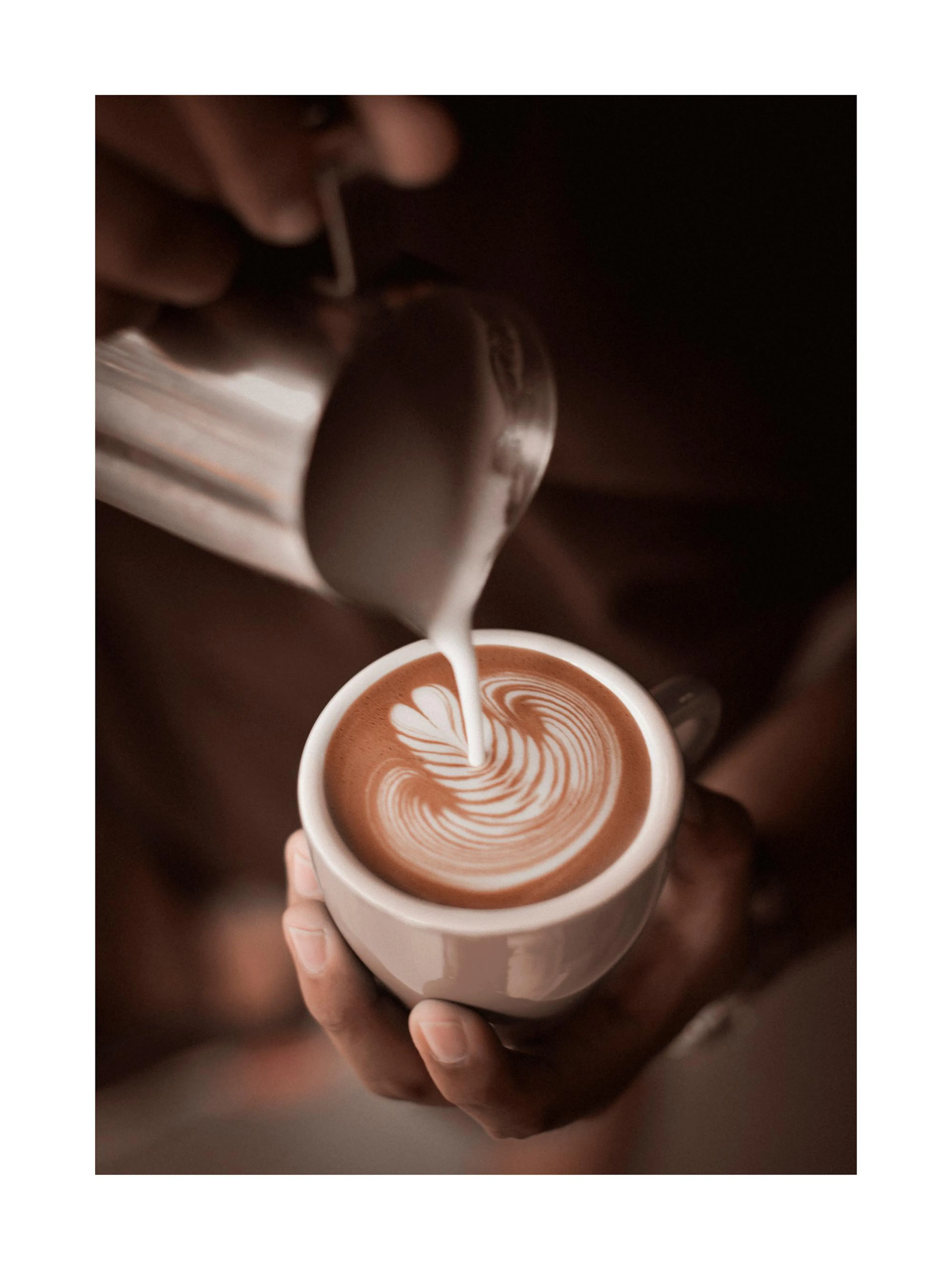 Een poster van een barista die latte art maakt in een kopje koffie, met een hartvormig patroon.