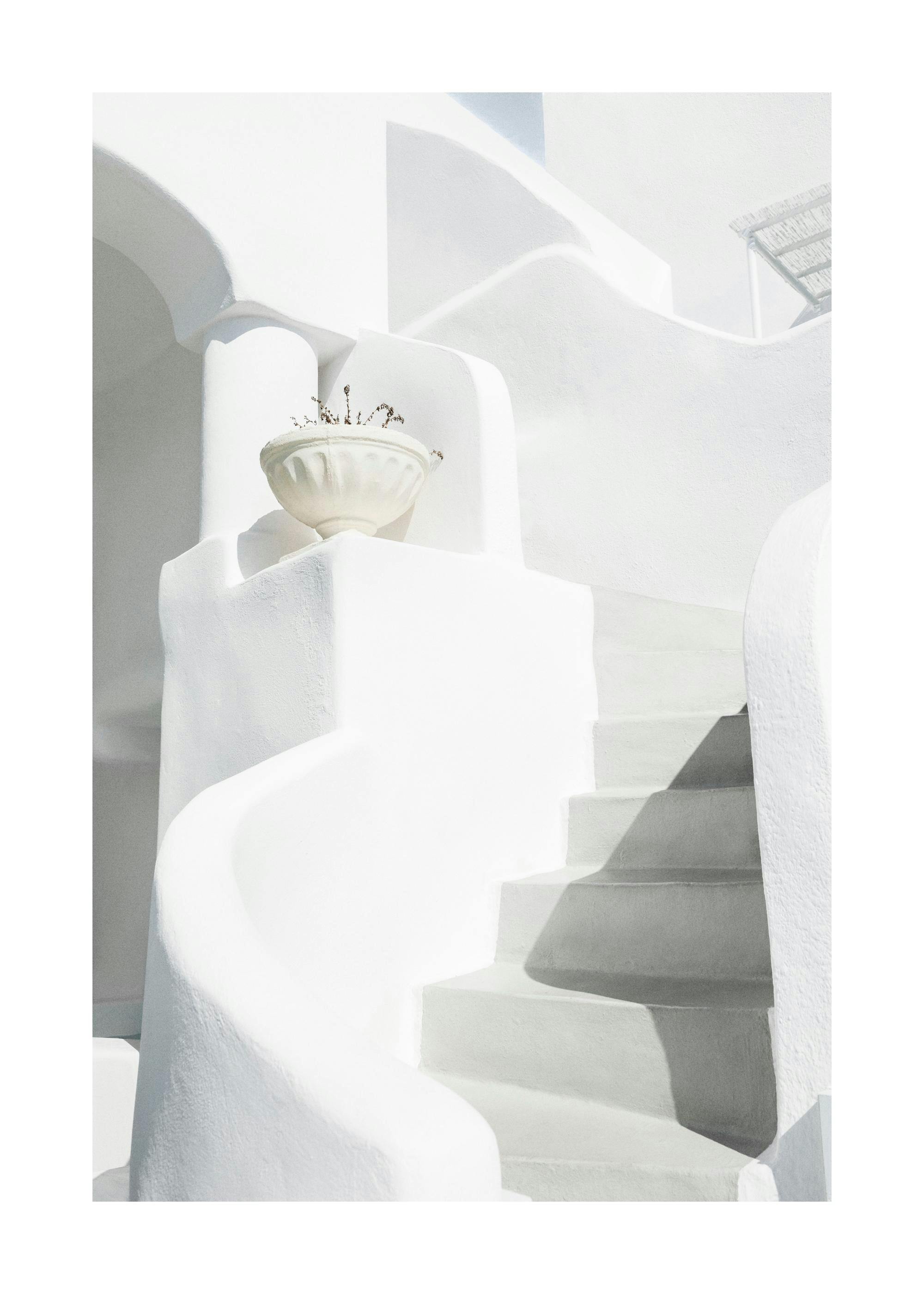 A poster featuring sun-drenched white architecture with curving walls and stairs in Greece, casting dark shadows.