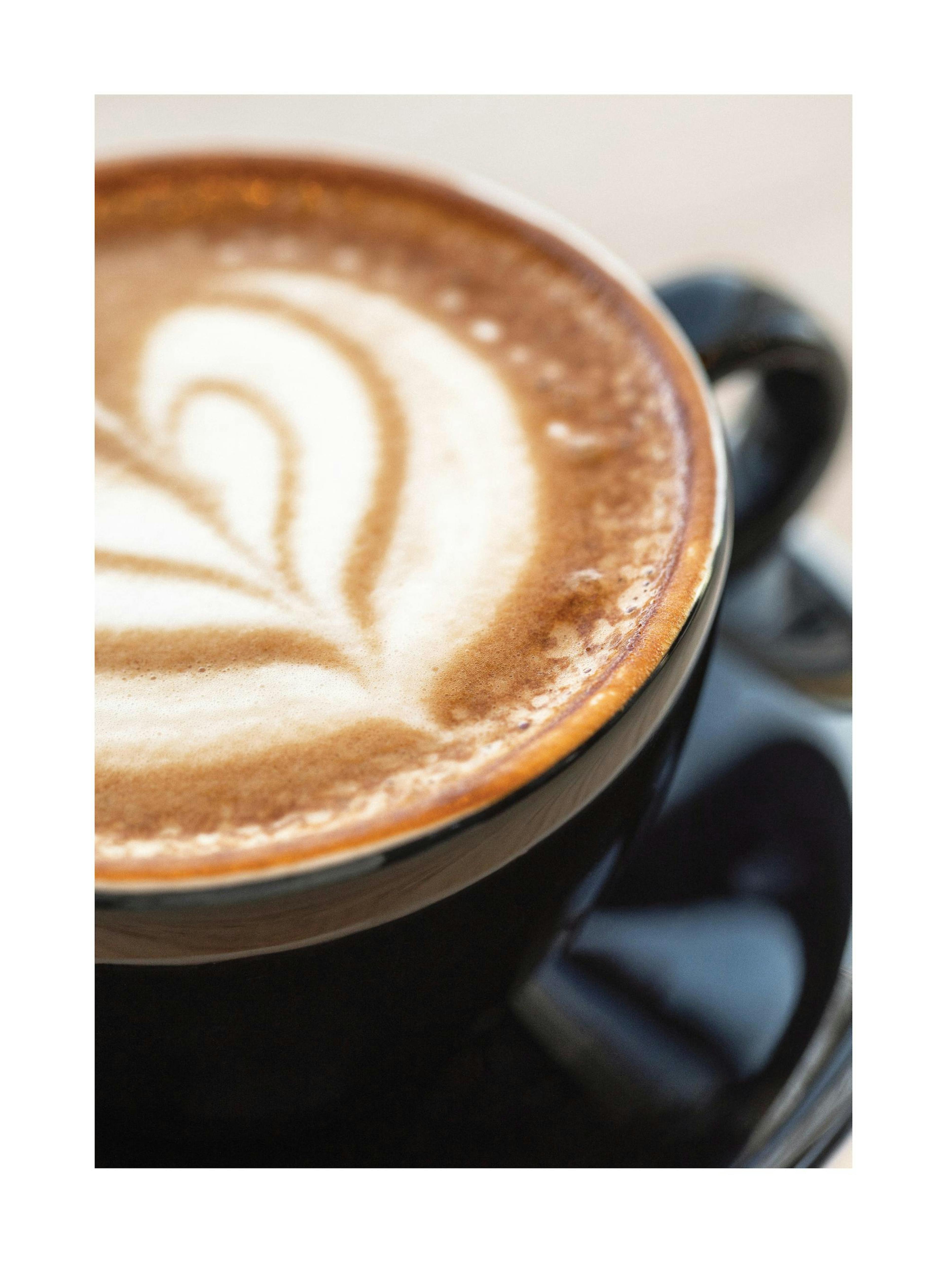 A poster featuring a close-up of a black coffee cup with latte art on a frothy surface.