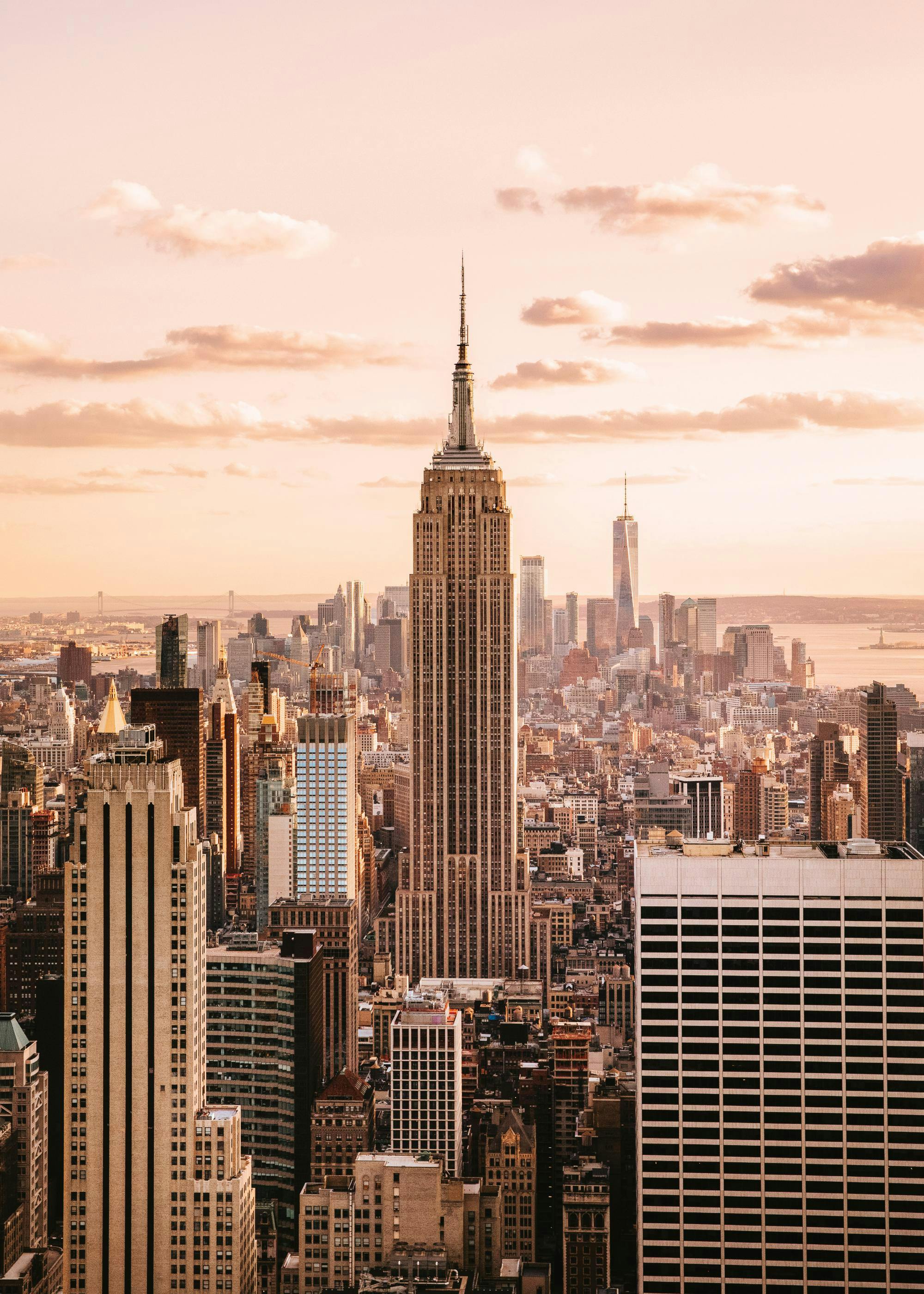 A poster featuring an aerial view of the New York City skyline at sunset, with the Empire State Building prominent.