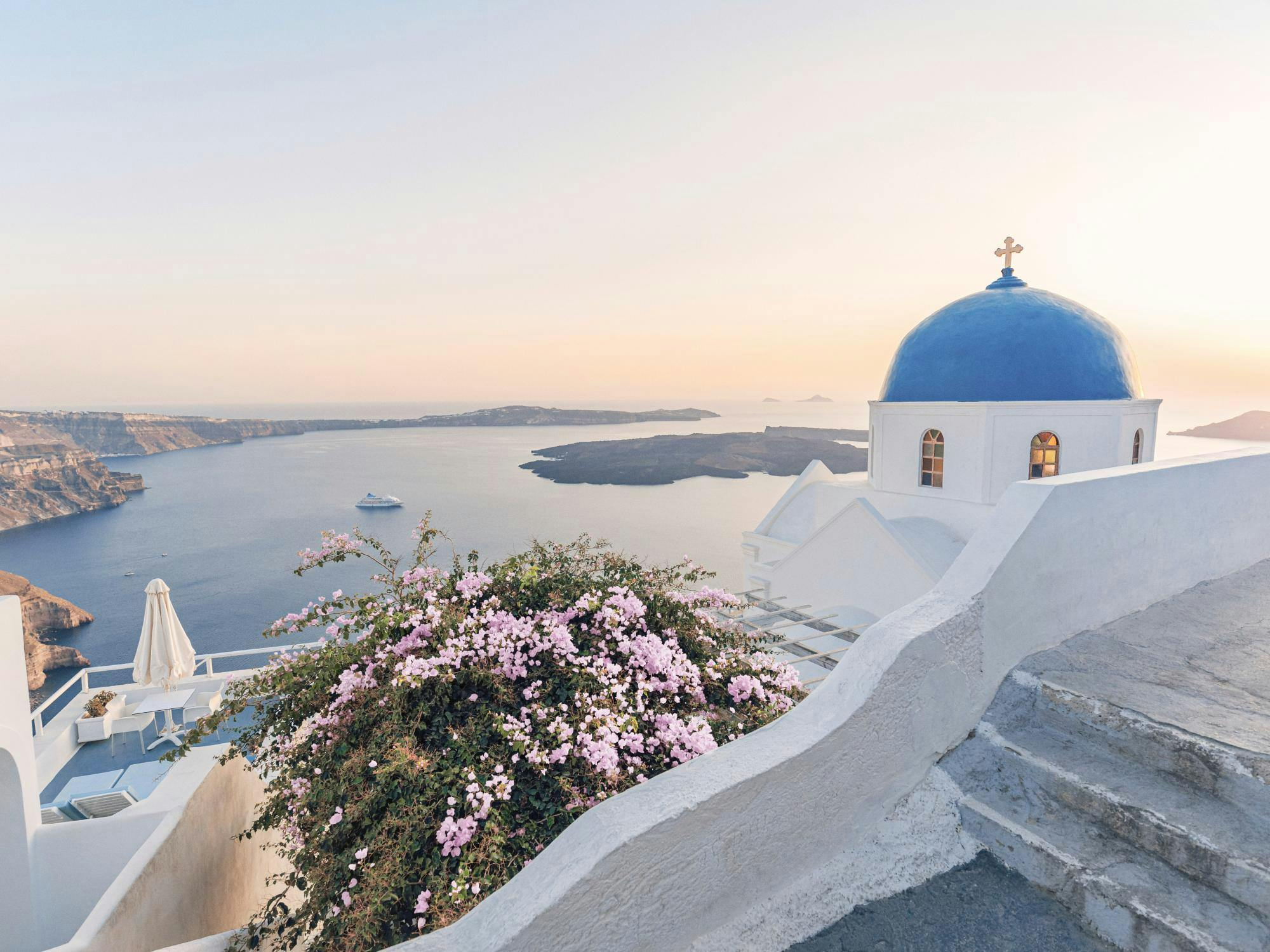 A stunning poster of a white building with a blue dome overlooking the sea and islands at sunset in Santorini.