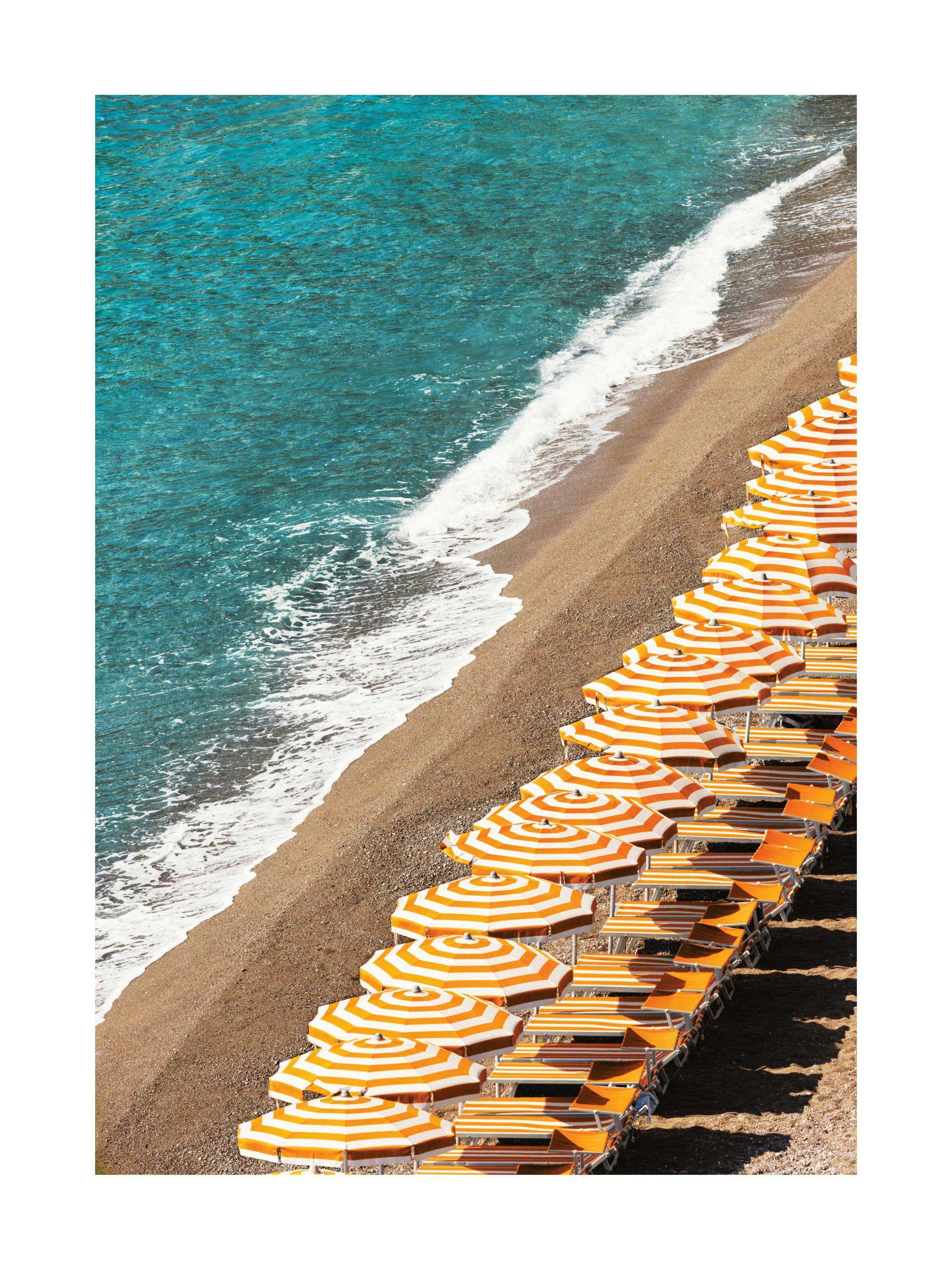 Poster dune plage de galets avec des rangées de parasols rayés orange et blanc, et la mer turquoise.