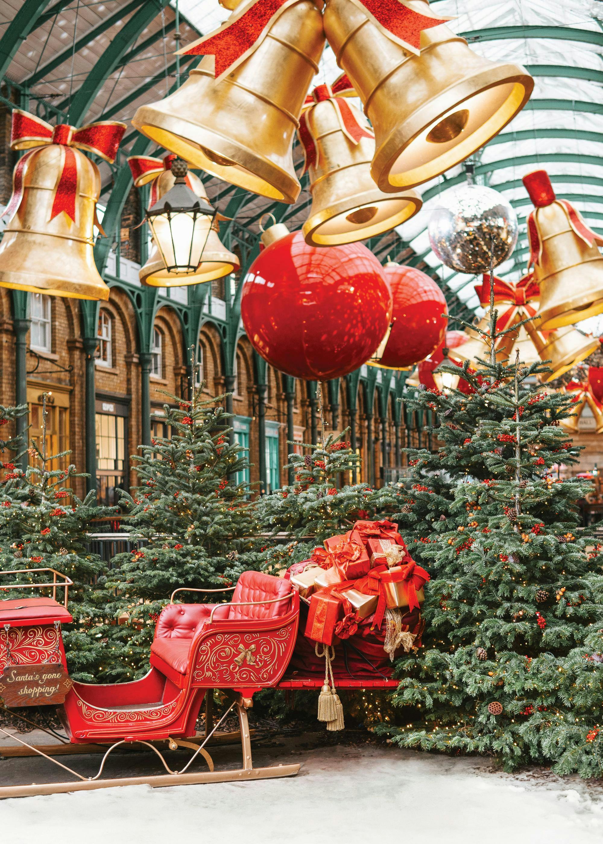 A festive Christmas market poster with a red sleigh, Christmas trees, and gold bells hanging from the ceiling.