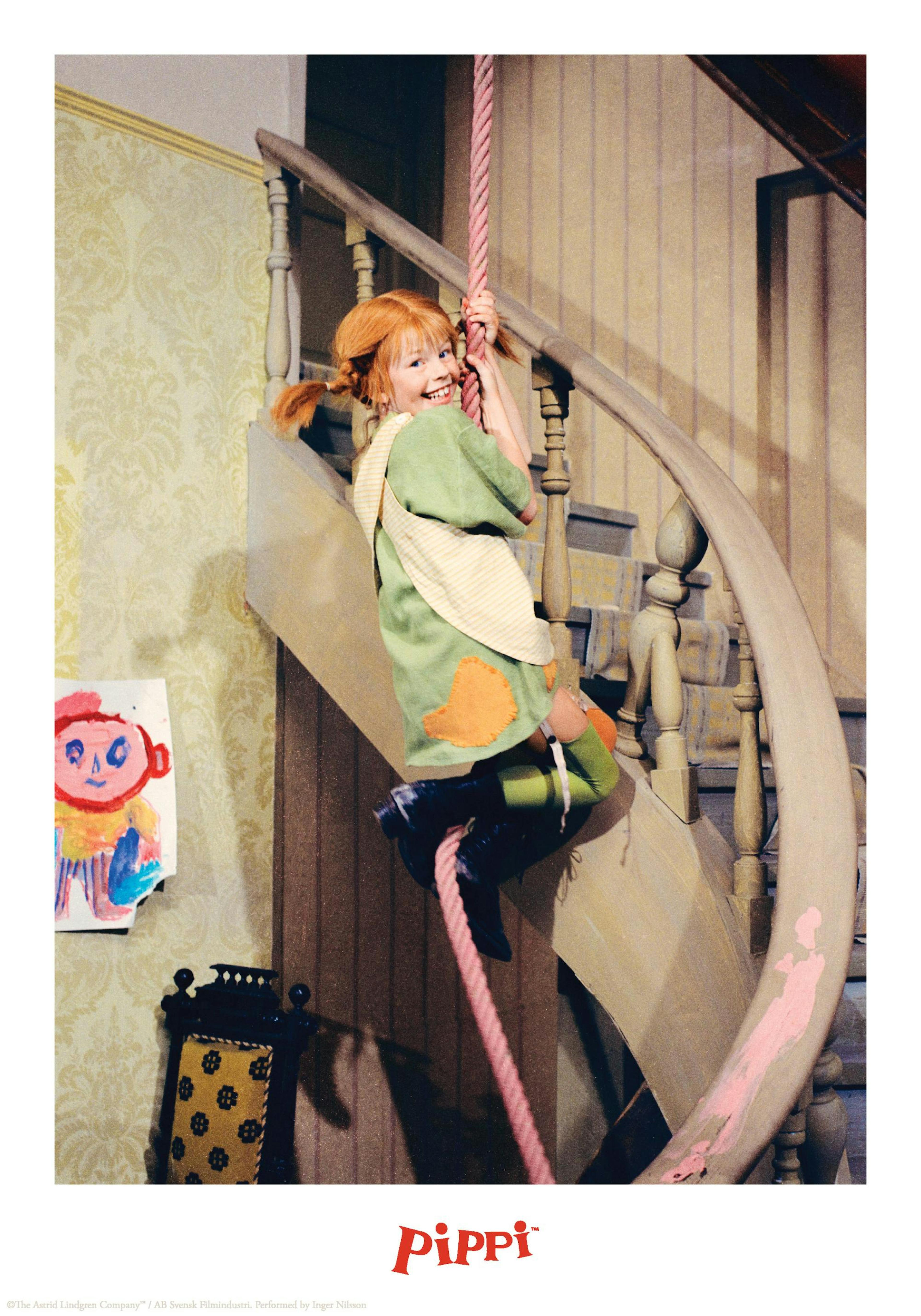 Poster Pippi Langstrumpf suspendu au-dessus dun meuble avec une lampe tressée et une poupée dans une chambre denfant.
