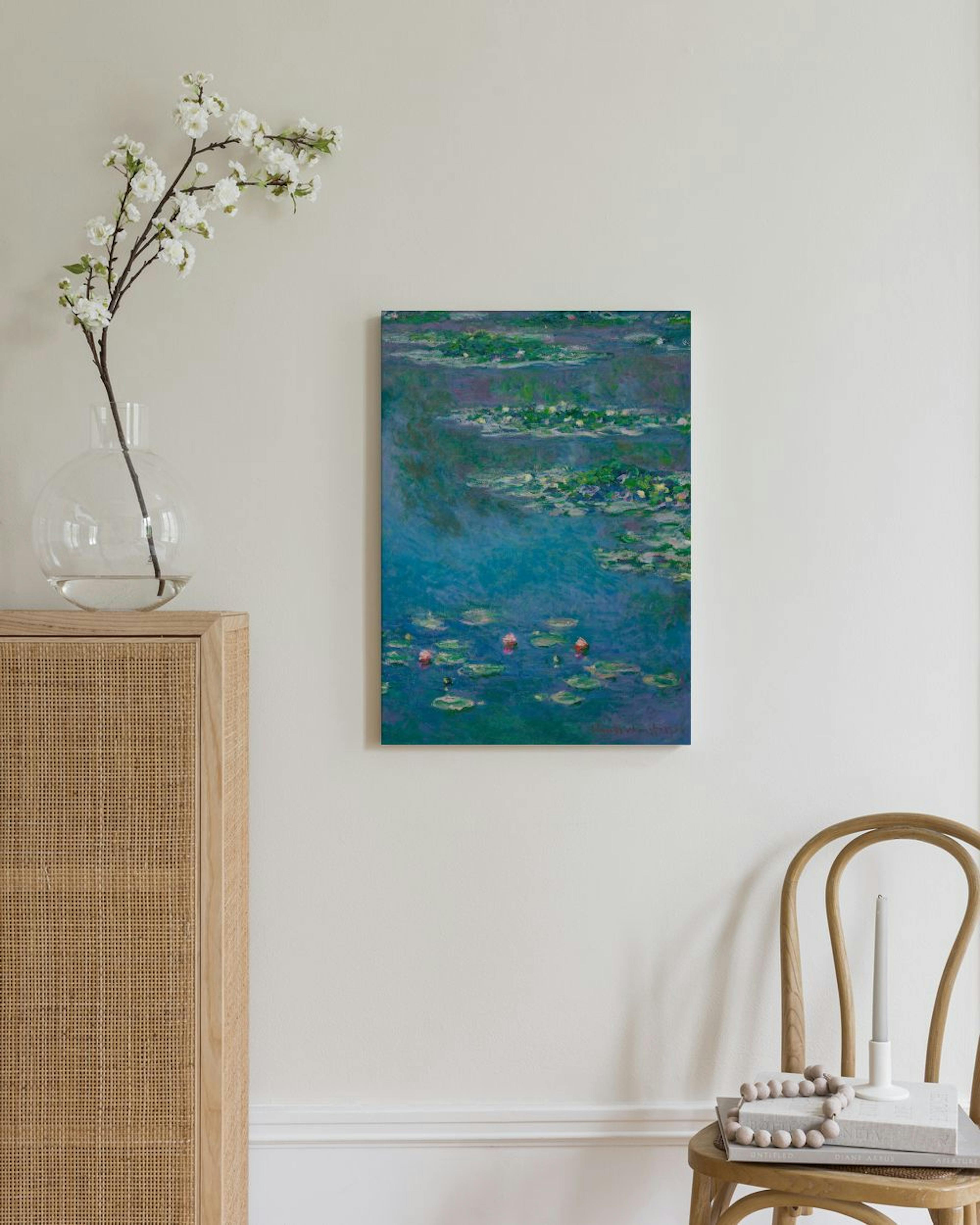 Monet-kanvaasi sinisestä lummelammesta, jossa on vihreitä lehtiä ja vaaleanpunaisia kukkia, modernissa huoneessa.