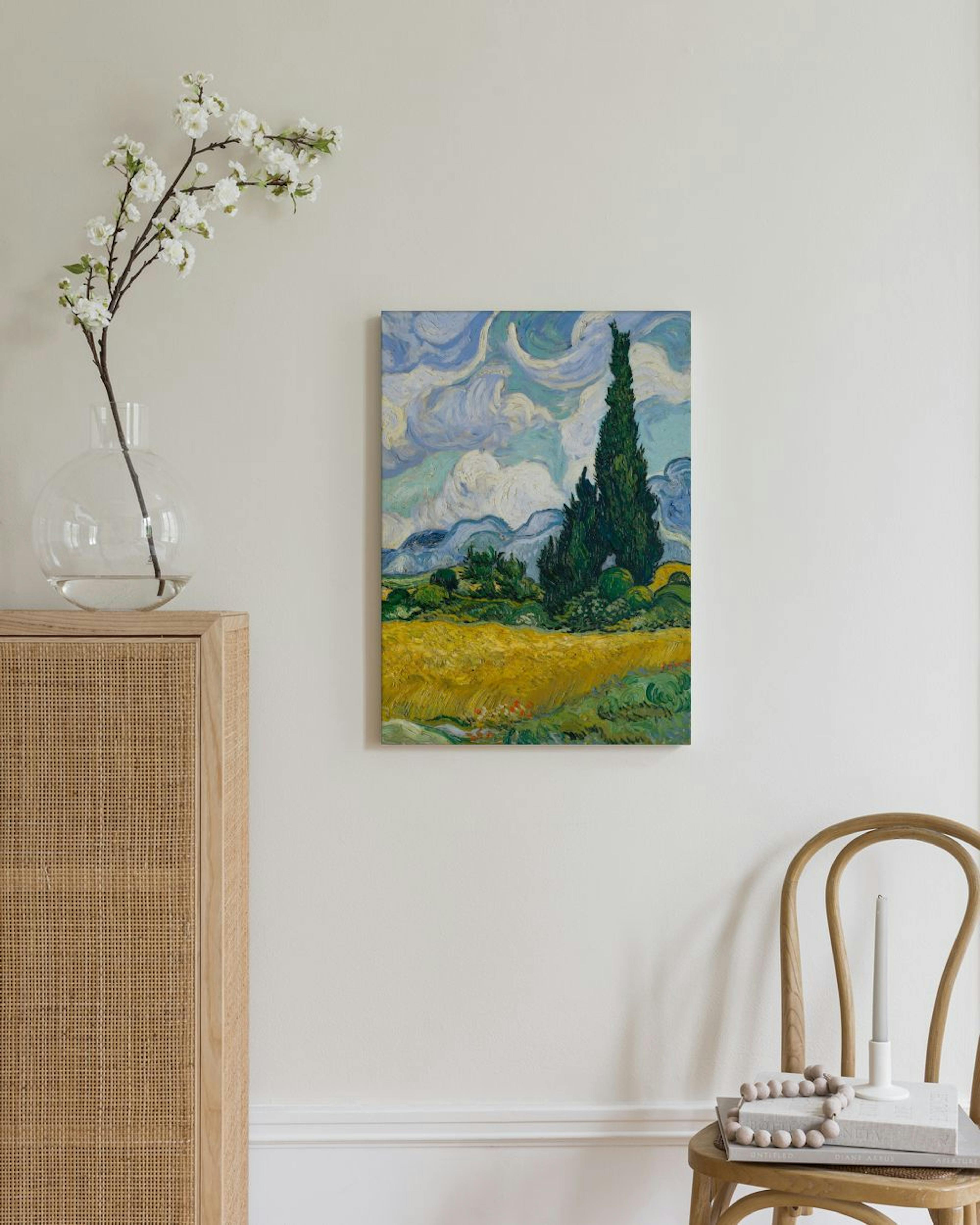 Kanvaasi, jossa on Van Goghin maalaus vihreistä sypressipuista ja keltaisesta vehnäpellosta, ripustettuna olohuoneen seinällä.