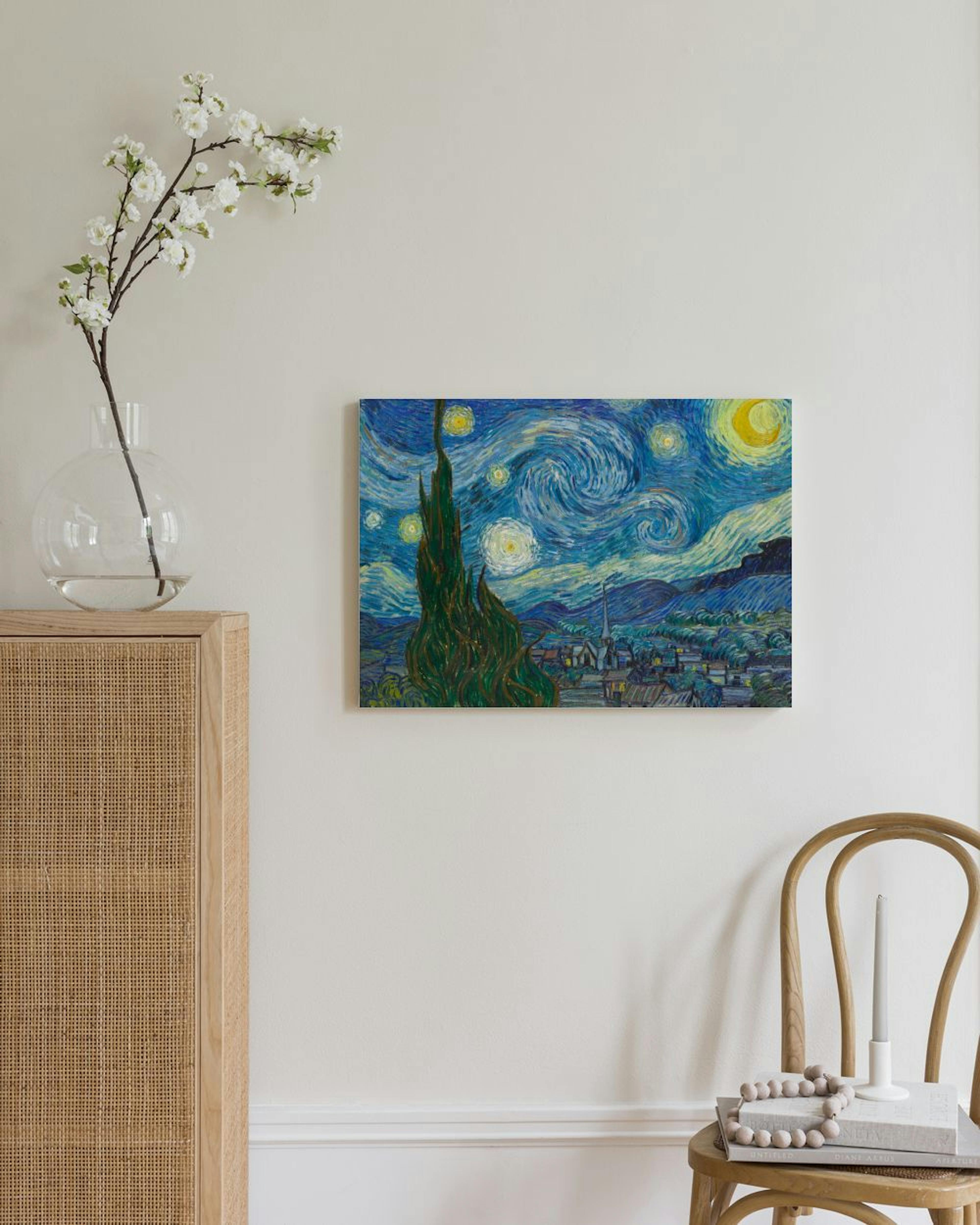Van Goghin Tähtiyö-kanvaasi rottinkikaapin ja puutuolin yläpuolella vaaleassa huoneessa.