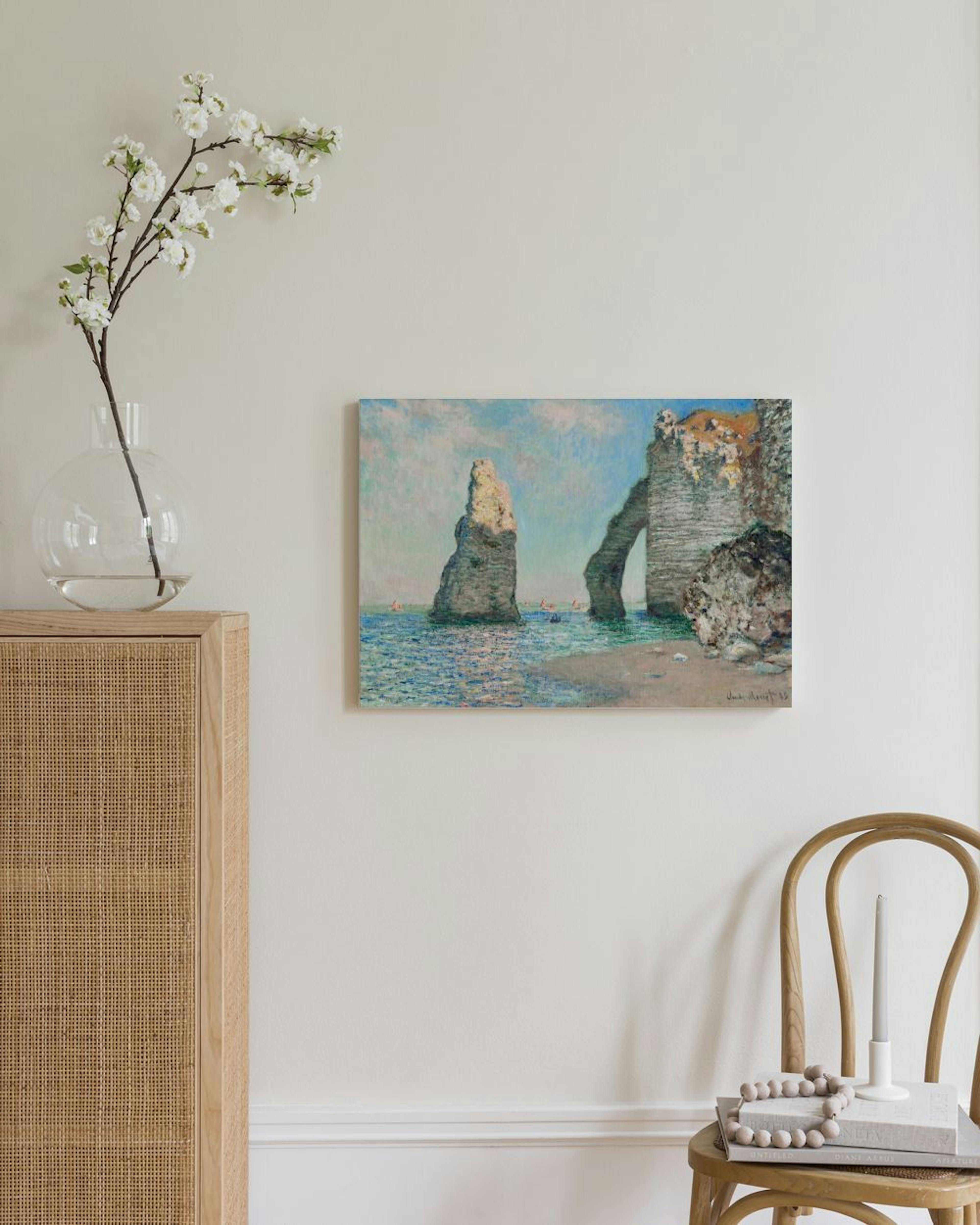 Monet-kanvaasi vaalealla seinällä. Maalauksessa on merenranta ja kaksi kallioista kaarta, joiden läpi näkyy taivas.