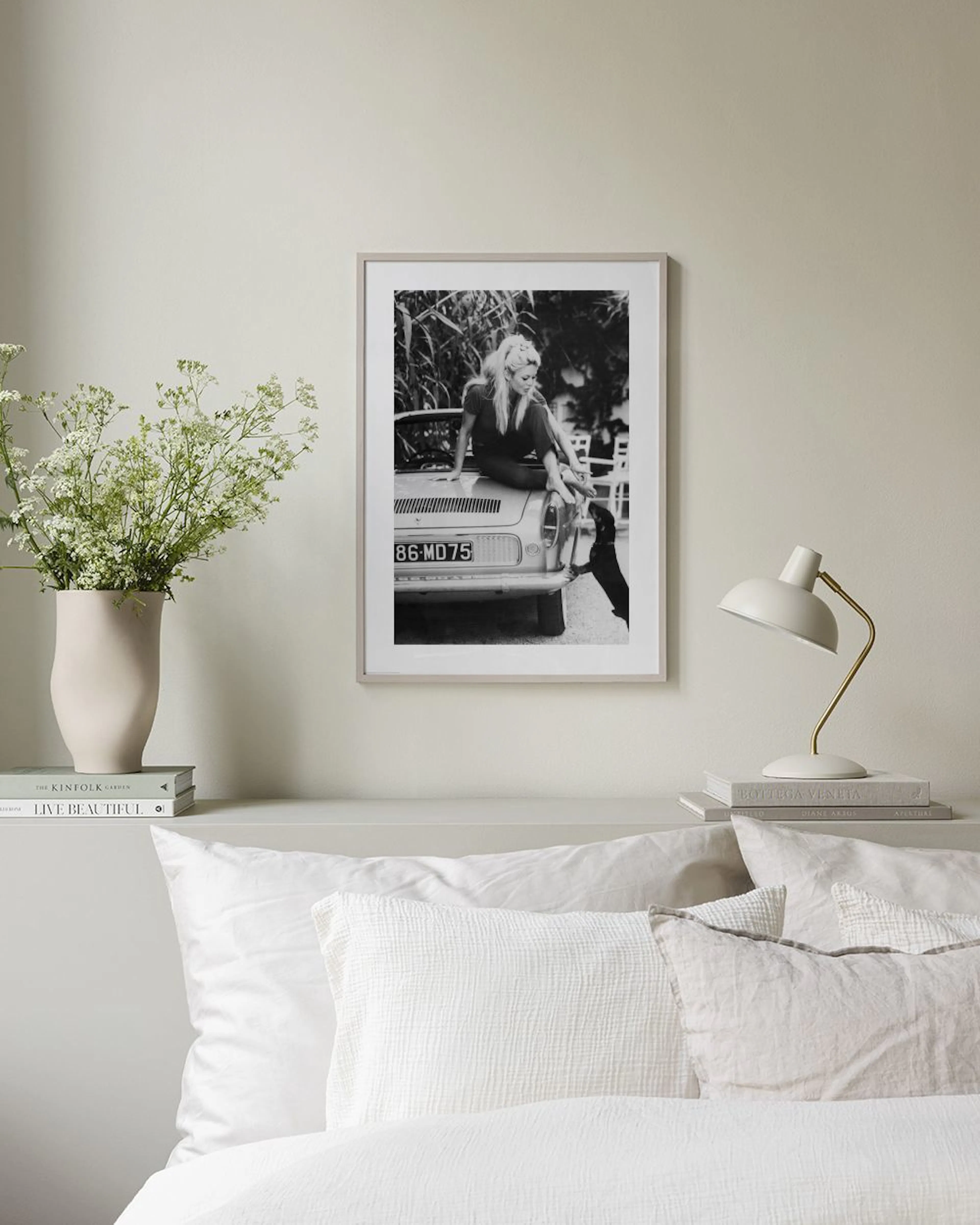 Poster noir et blanc dune femme assise sur une voiture, interagissant avec un chien, affiché dans un bureau moderne.
