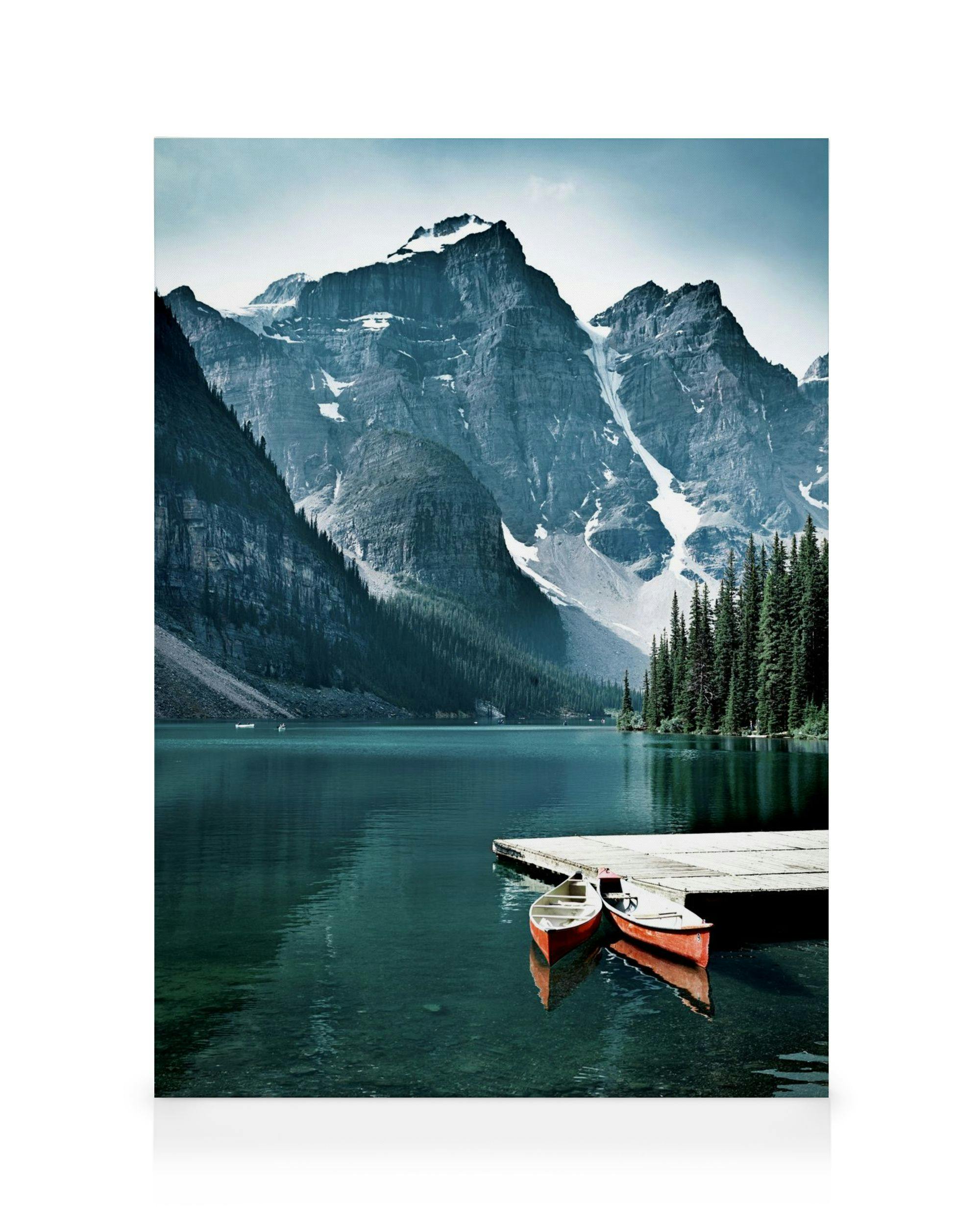 A canvas showing two red canoes tied to a wooden dock on a calm lake, surrounded by snow-capped mountains and green pine trees.