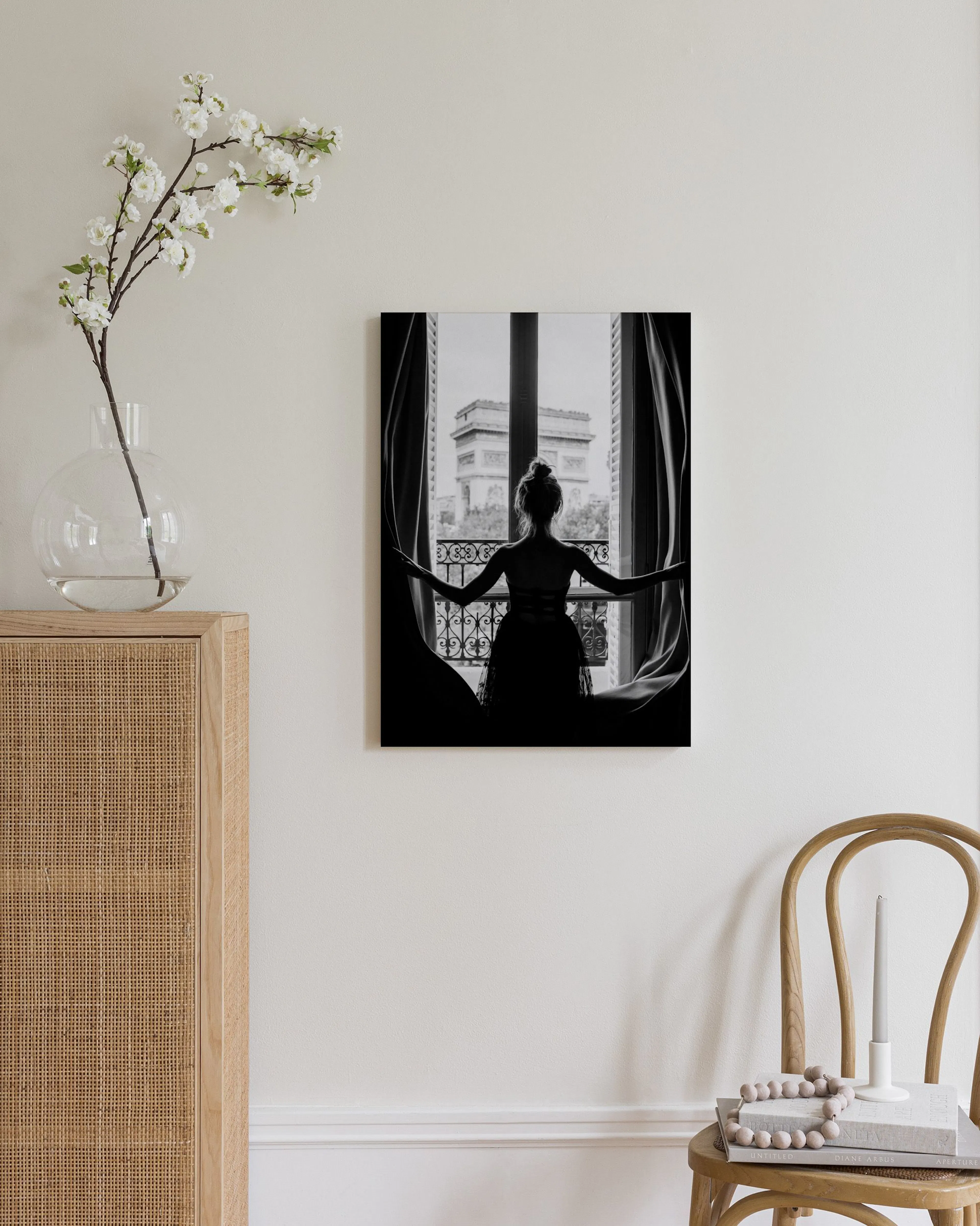 Toile noir et blanc d’une femme admirant lArc de Triomphe depuis une fenêtre, accrochée dans un salon moderne.