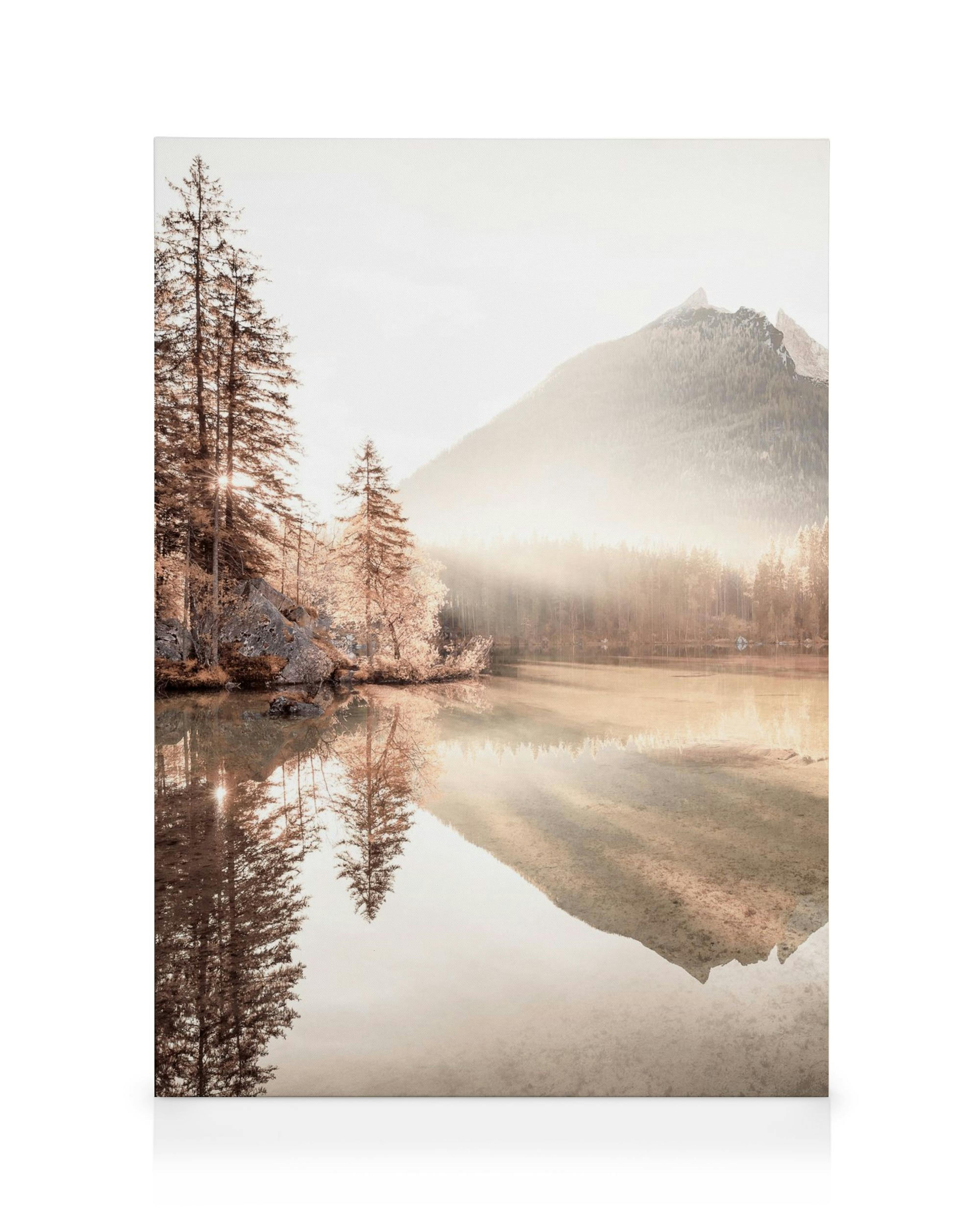 Een canvas met een mistig berglandschap met spiegelende bomen en zonlicht in een kalm meer.