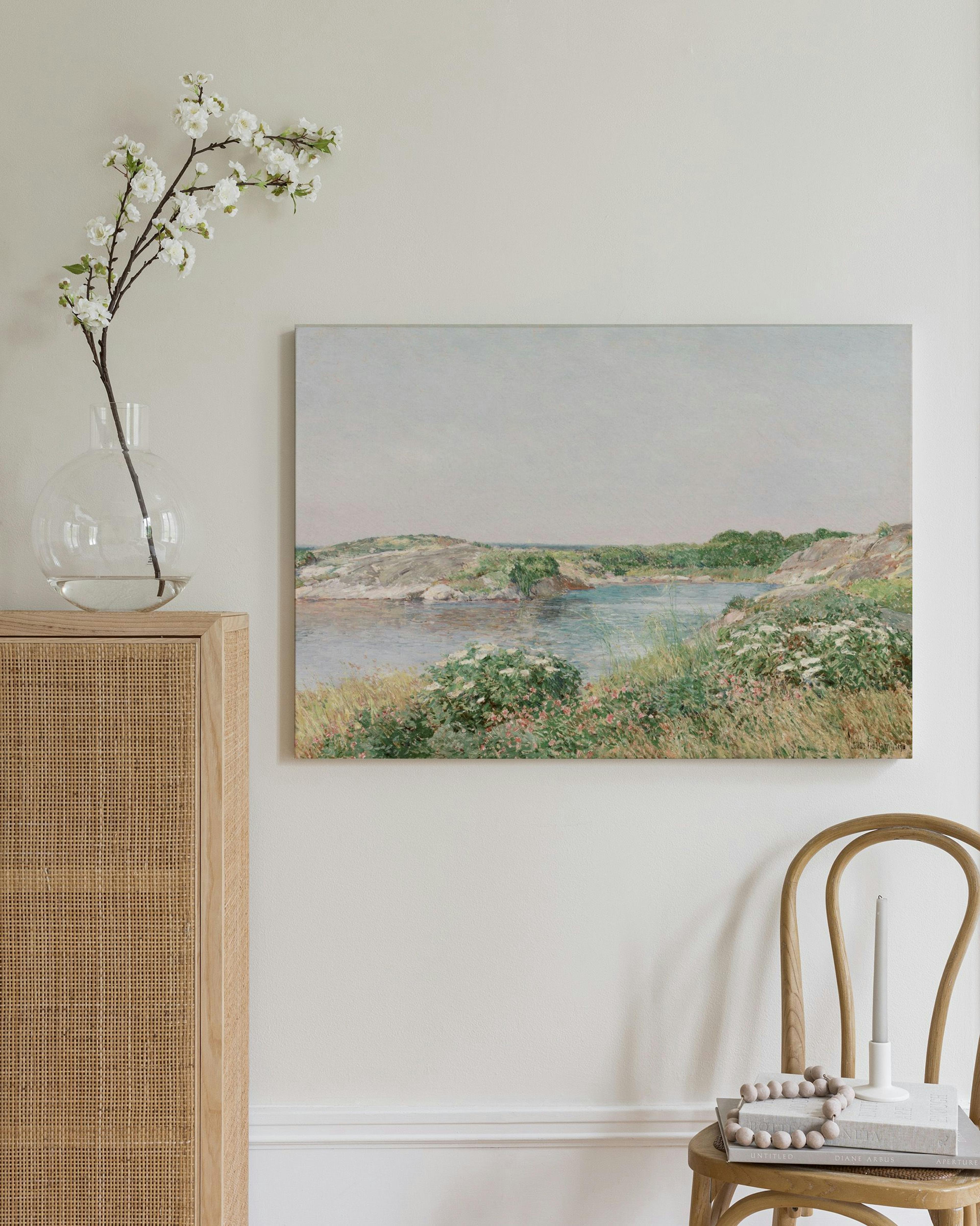 Toile paysage marin canadien avec eau bleue, herbe verte, rochers, et buissons fleuris roses et blancs.