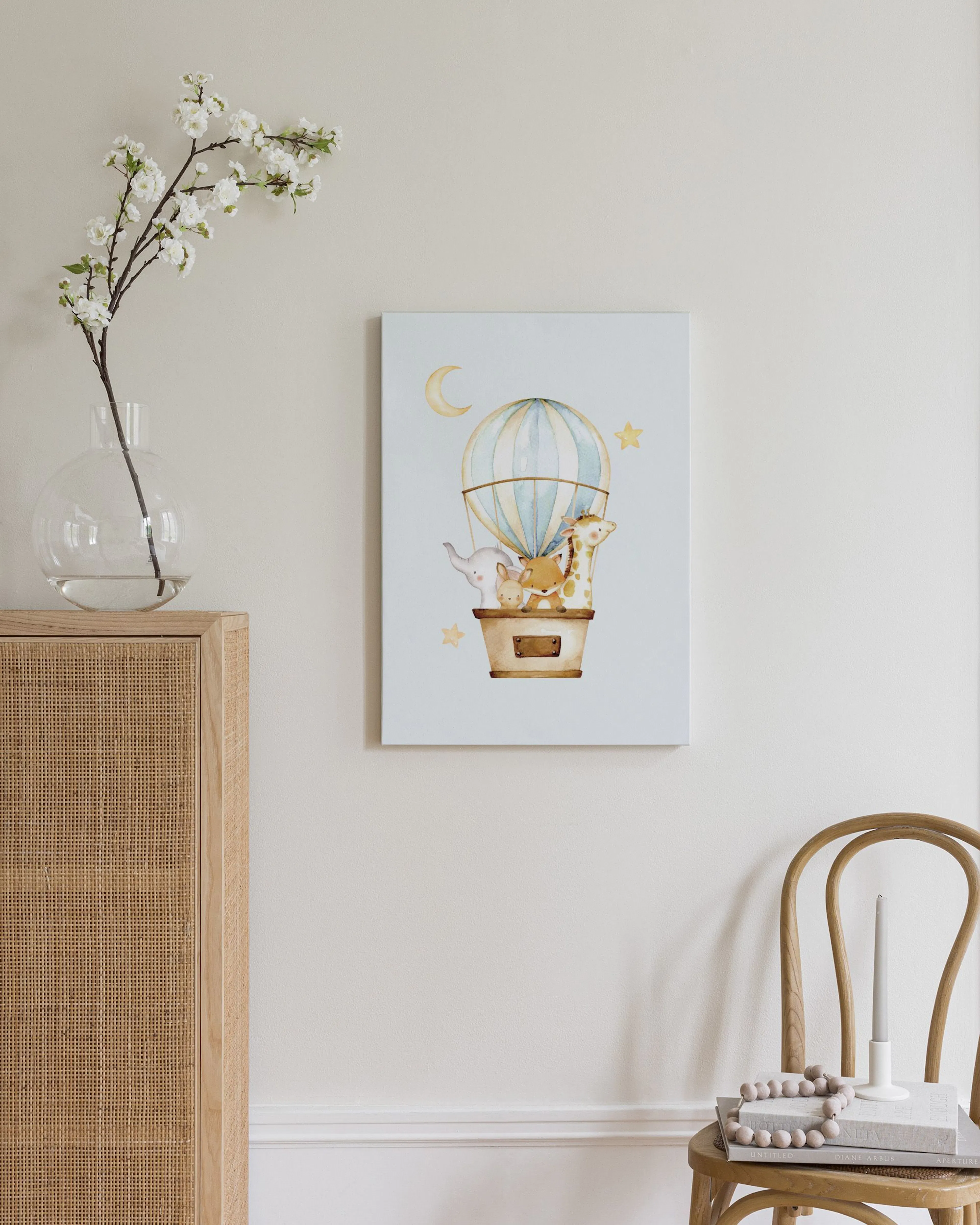 Toile pour chambre denfant avec des animaux mignons dans une montgolfière, accrochée au-dessus dune commode en bois.