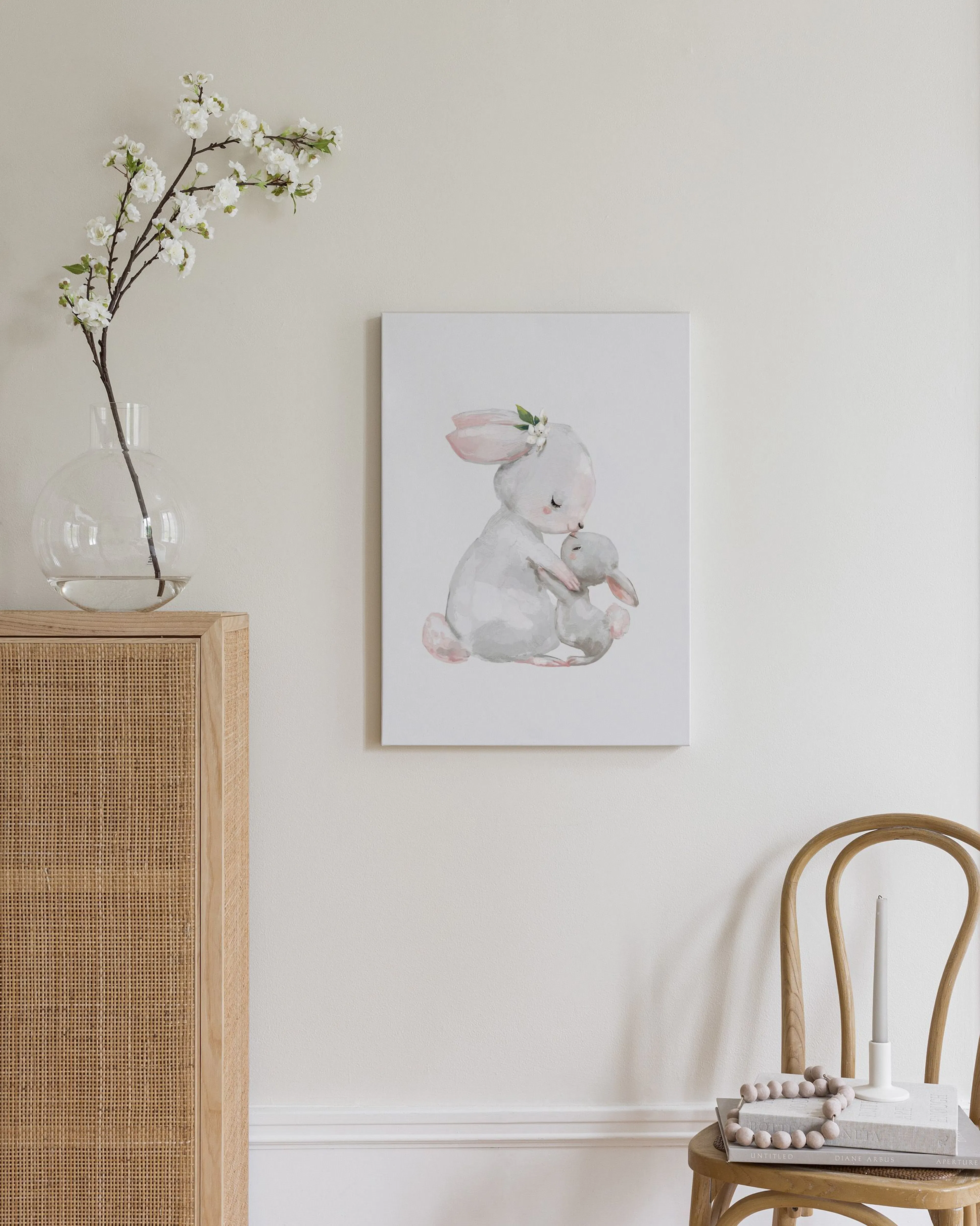 Toile murale dun lapin gris et rose câlinant son petit, accrochée au-dessus dune commode en bois dans une chambre.