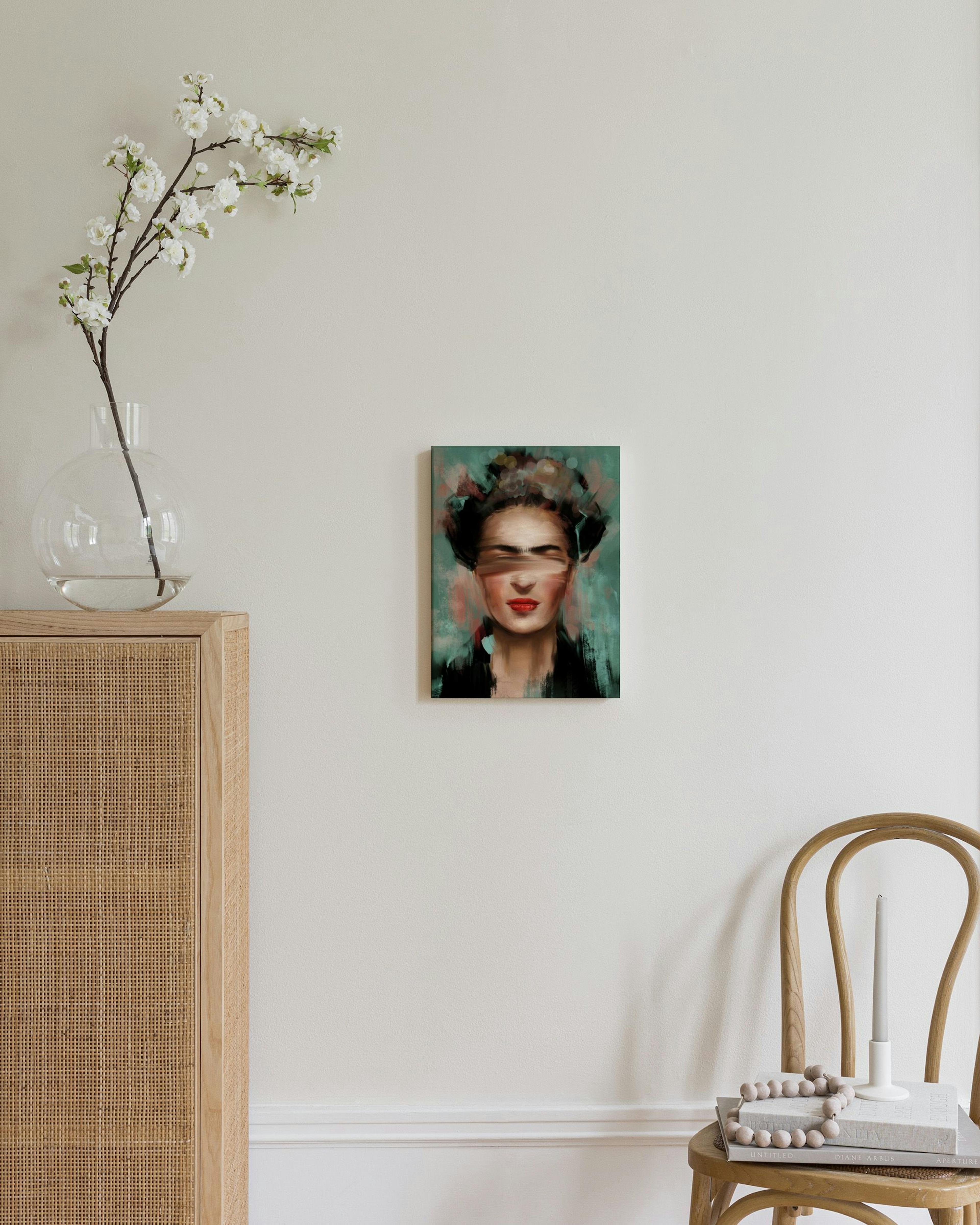 Canvas van het gezicht van Frida Kahlo met rode lippen en geblurde ogen, hangend boven een stoel in een lichte kamer.