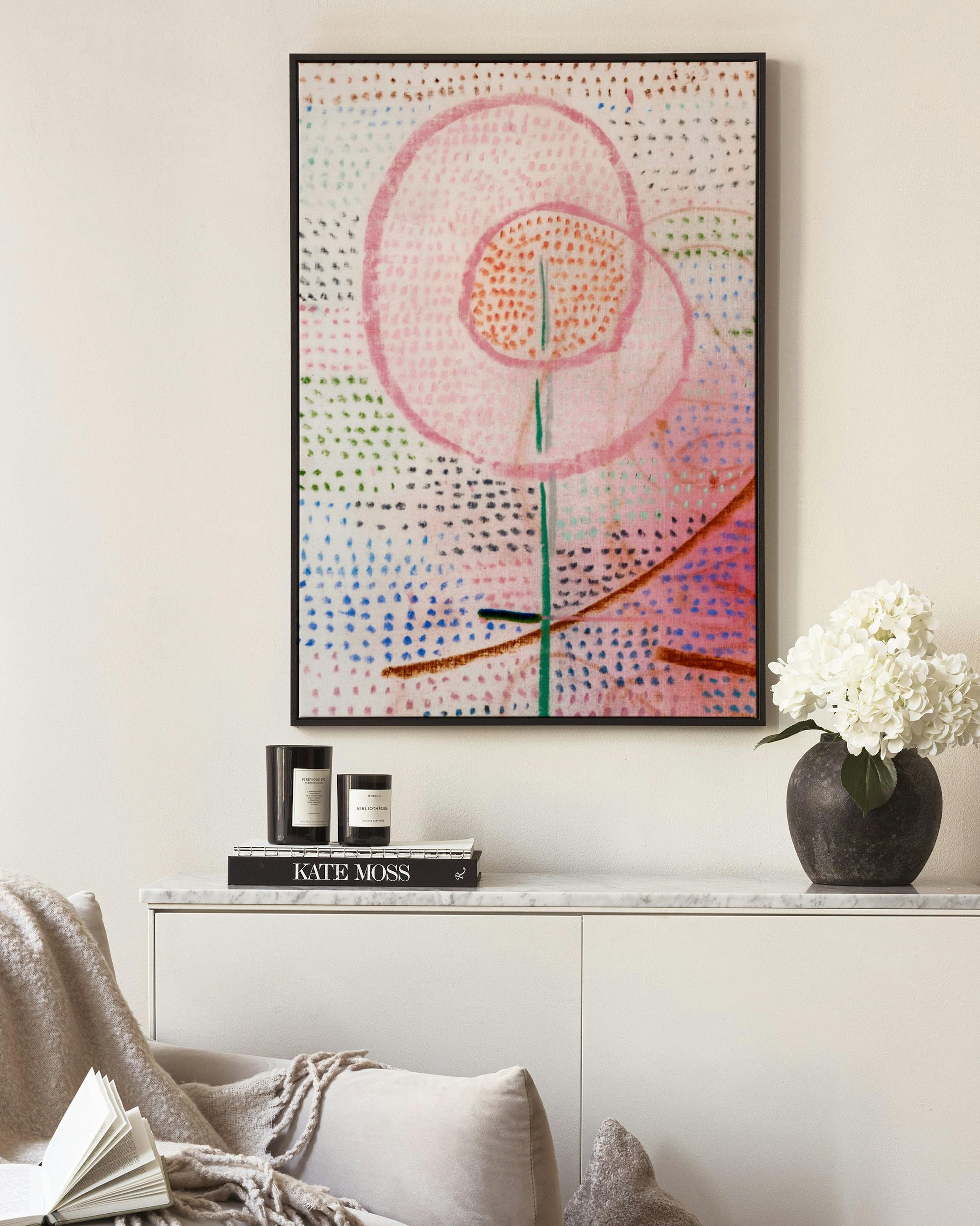 Pânză decorativă cu o floare roz stilizată, cu petale rotunde și fundal punctat multicolor.