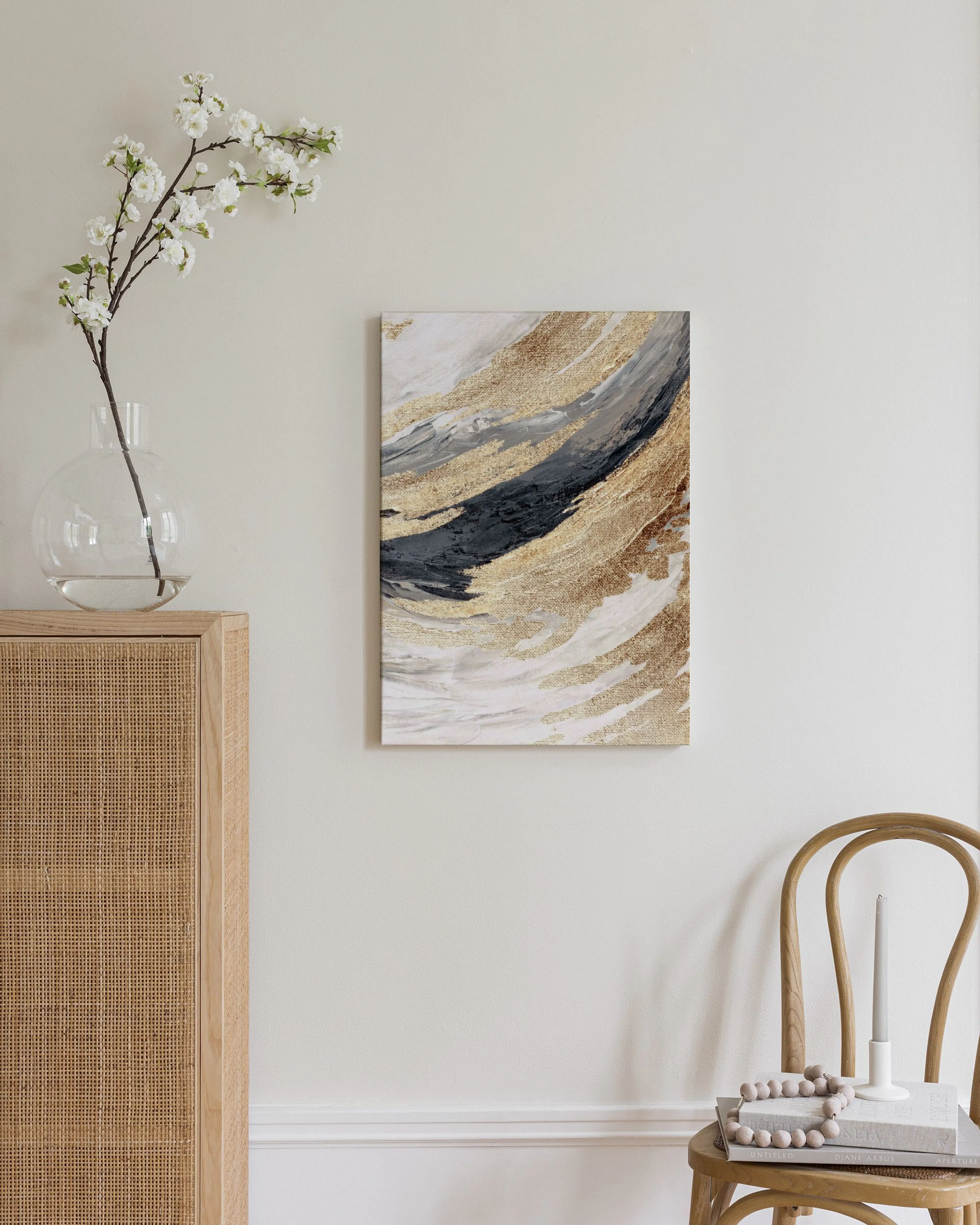 Canvas met goudkleurige, grijze en zwarte organische vormen en witte lijnen, hangend in een lichte woonkamer.