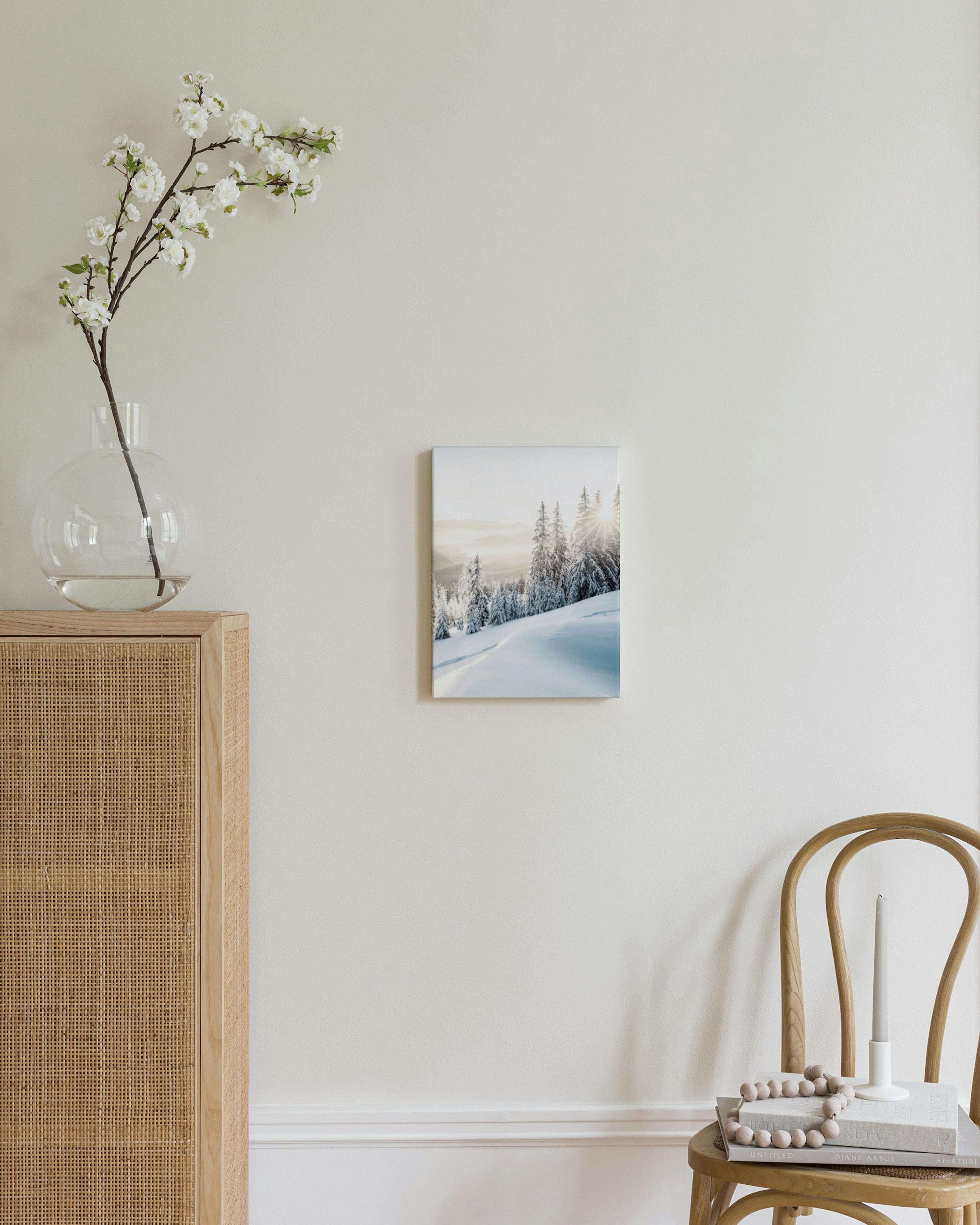 Obraz na płótnie z zimowym krajobrazem górskim o wschodzie słońca, wiszący nad drewnianą komodą w sypialni.