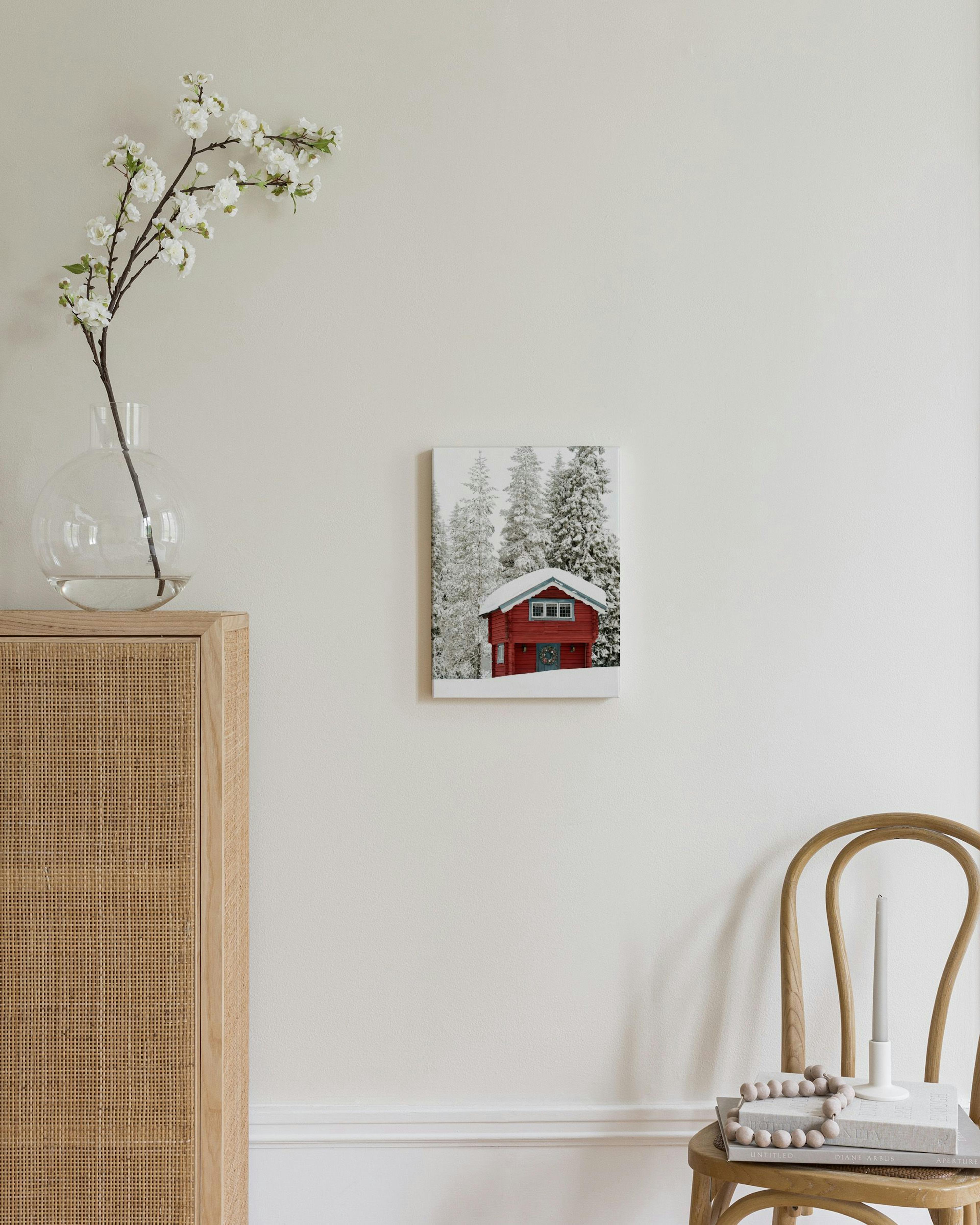 Kanvaasi punaisesta mökistä lumisen metsän keskellä makuuhuoneen lipaston yllä.