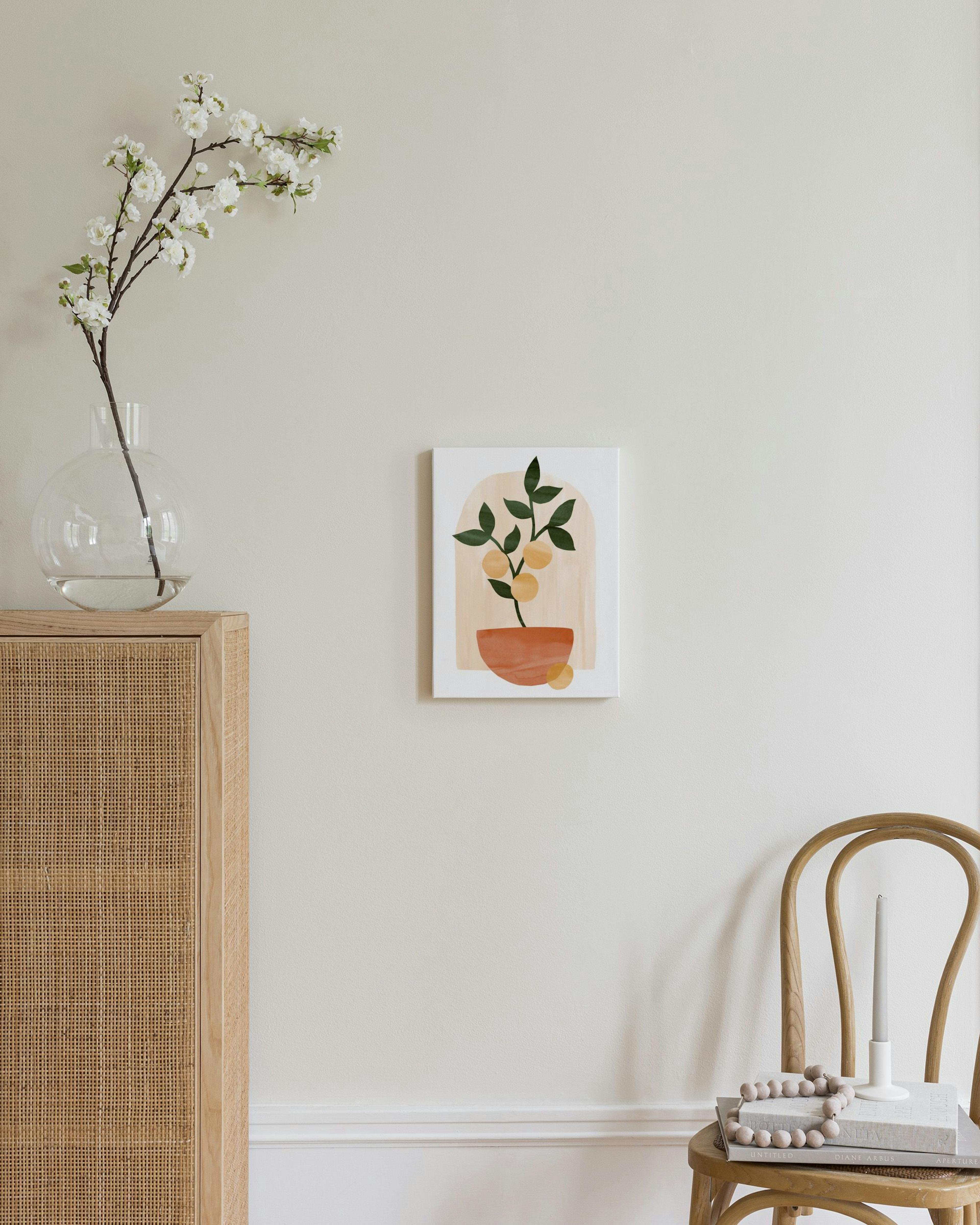 Canvas met een illustratie van een oranje boom in een pot, hangend boven een houten dressoir met rieten details.