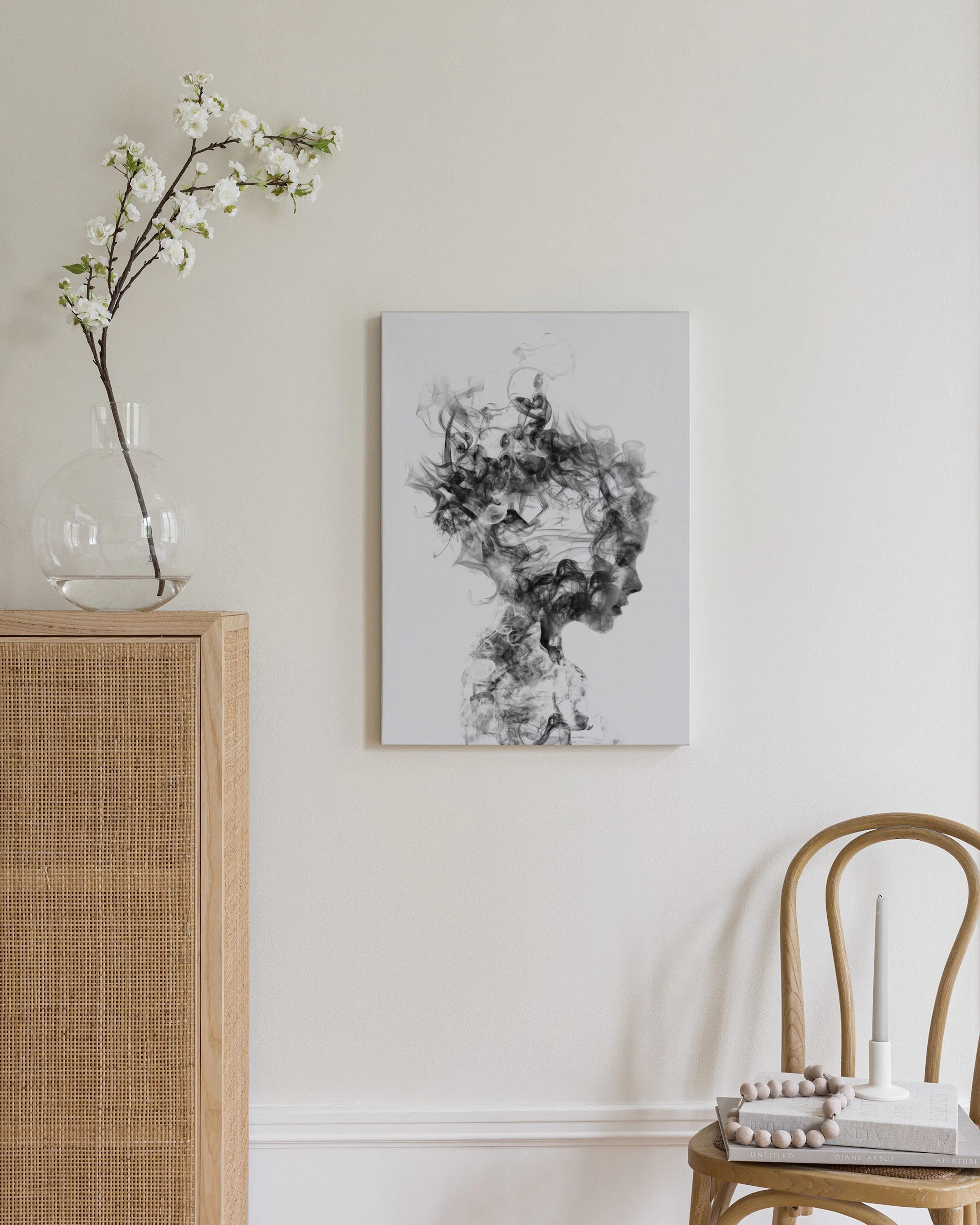 Toile murale, silhouette de visage féminin en volutes de fumée noire et grise, accrochée au-dessus dun buffet en bois.