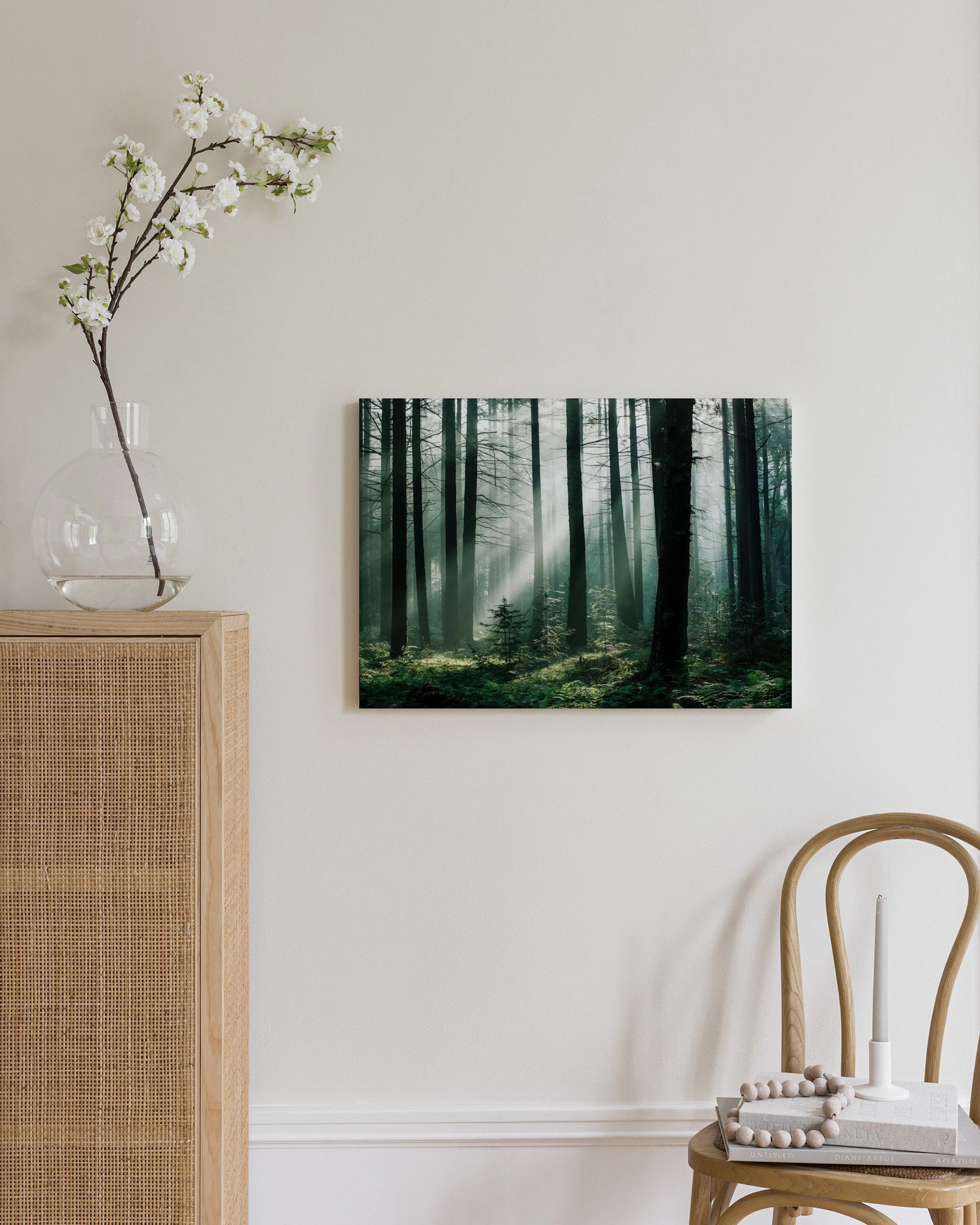 Toile murale dune forêt brumeuse avec des rayons de lumière à travers les arbres, suspendue au-dessus dune commode en bois clair