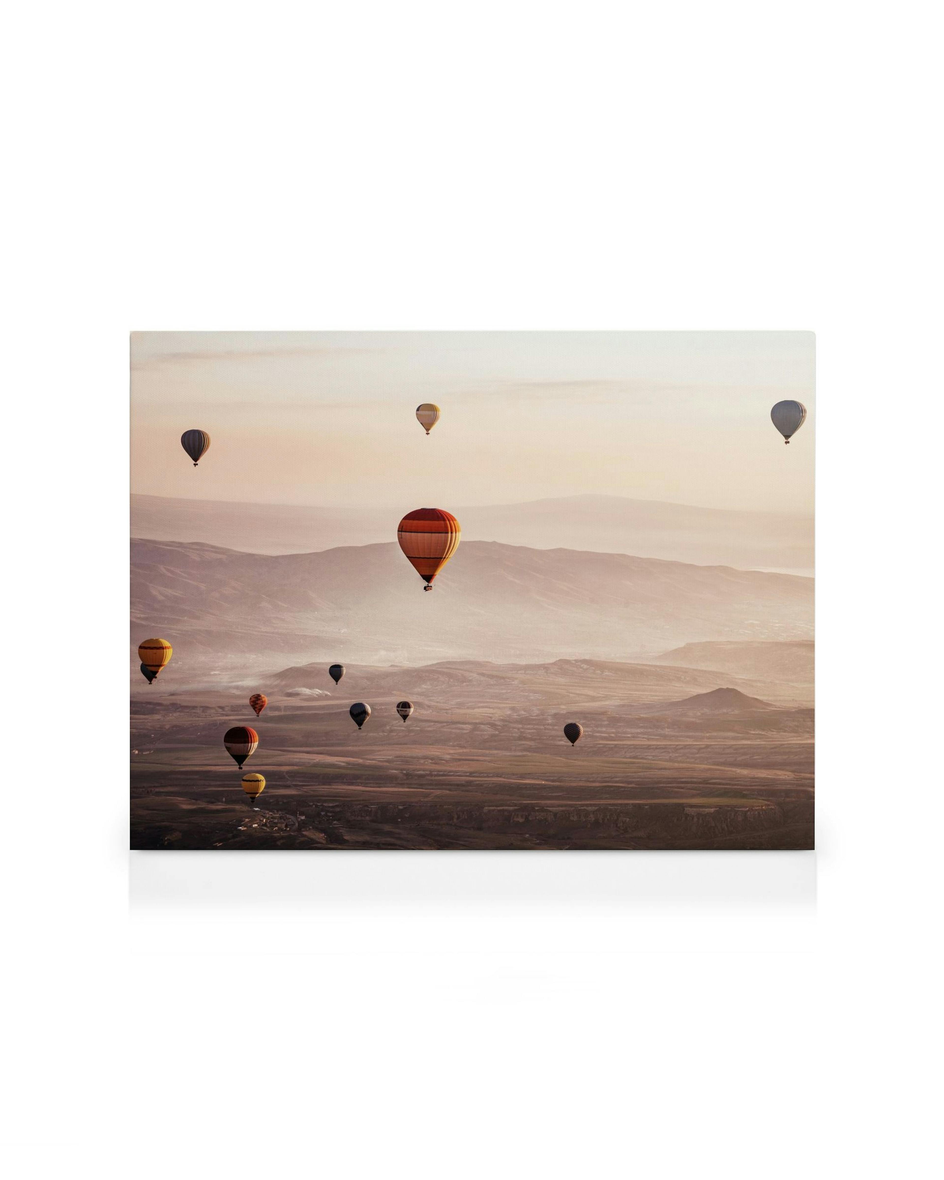 A canvas showing a scenic view of hot air balloons floating over mountainous terrain at sunrise.