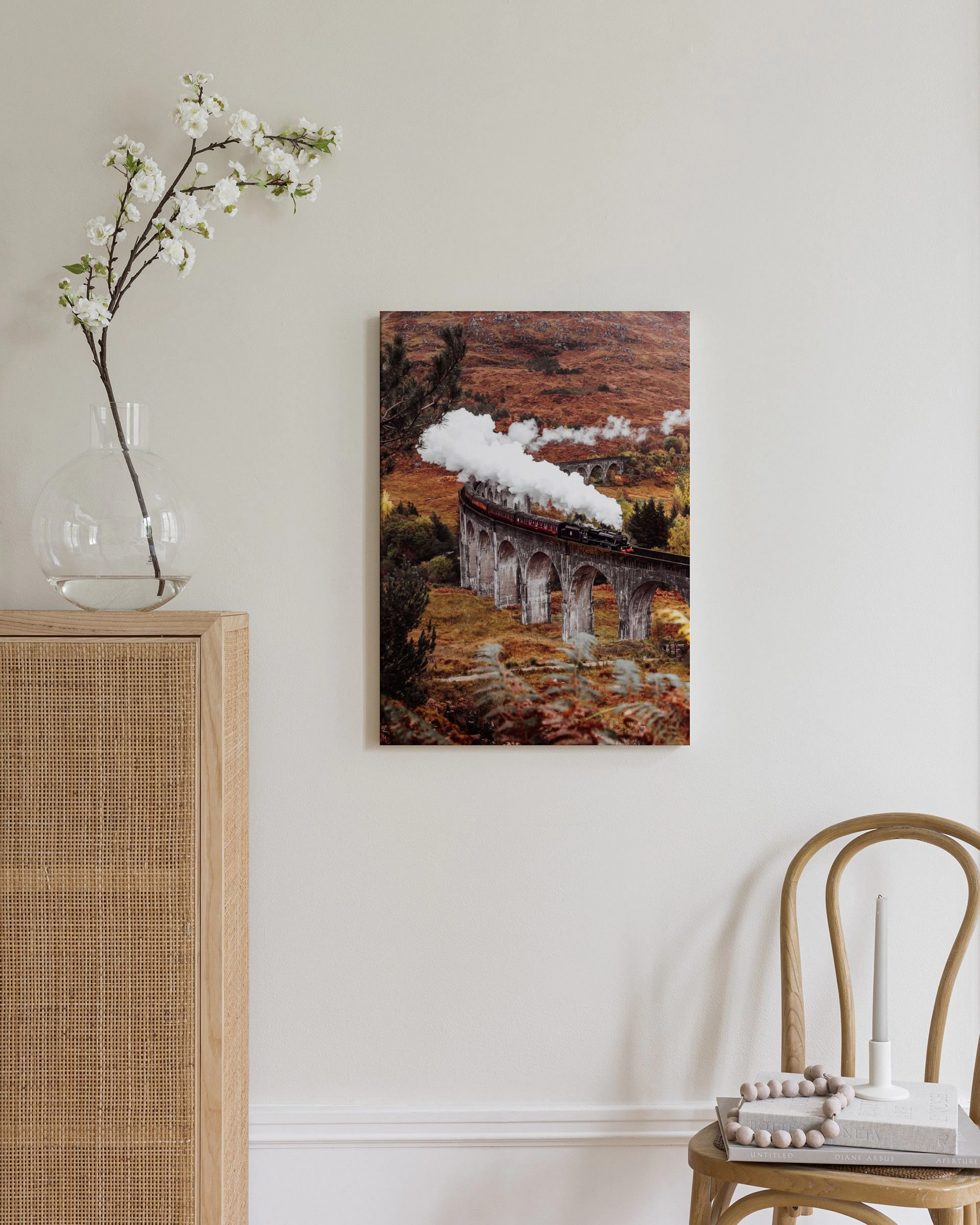 Canvas van een stoomtrein op een stenen viaduct, hangend boven een houten dressoir met lamp en decoratie.