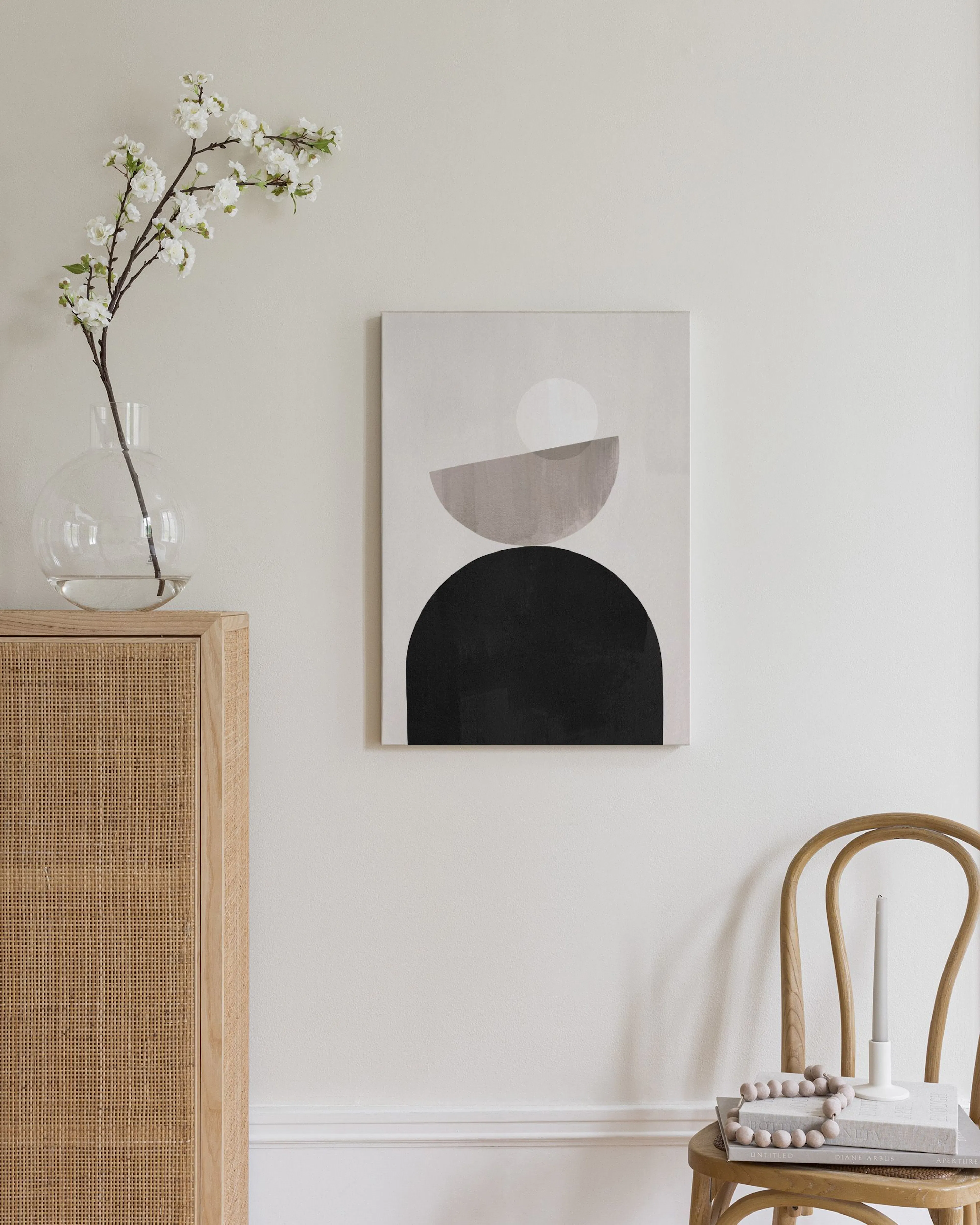 Toile murale abstraite avec formes géométriques en noir, gris et blanc, suspendue au-dessus dun buffet en bois clair dans une ch