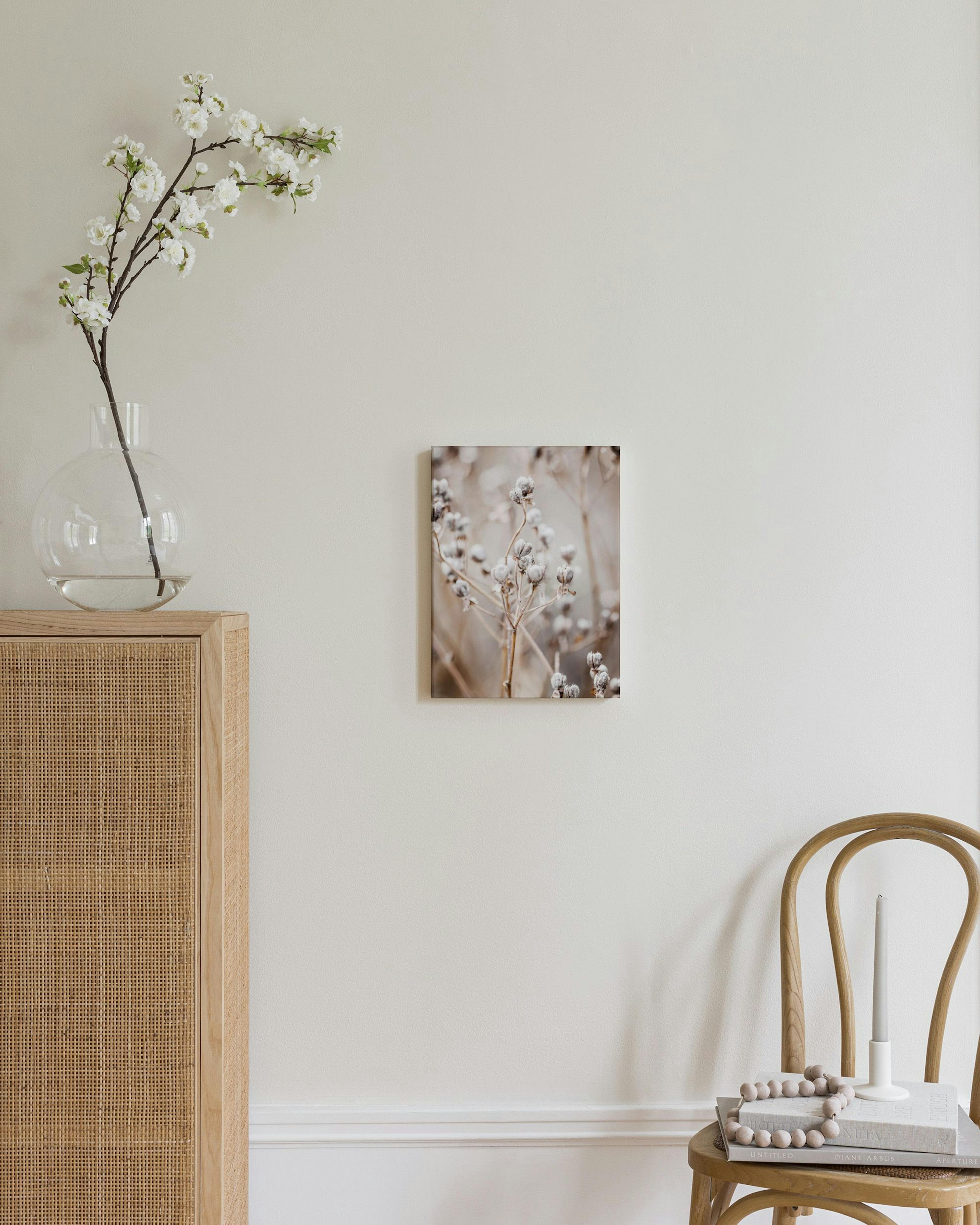 Canvas of dried plant pods on a beige background, displayed in a neutral-toned room with a white vase.