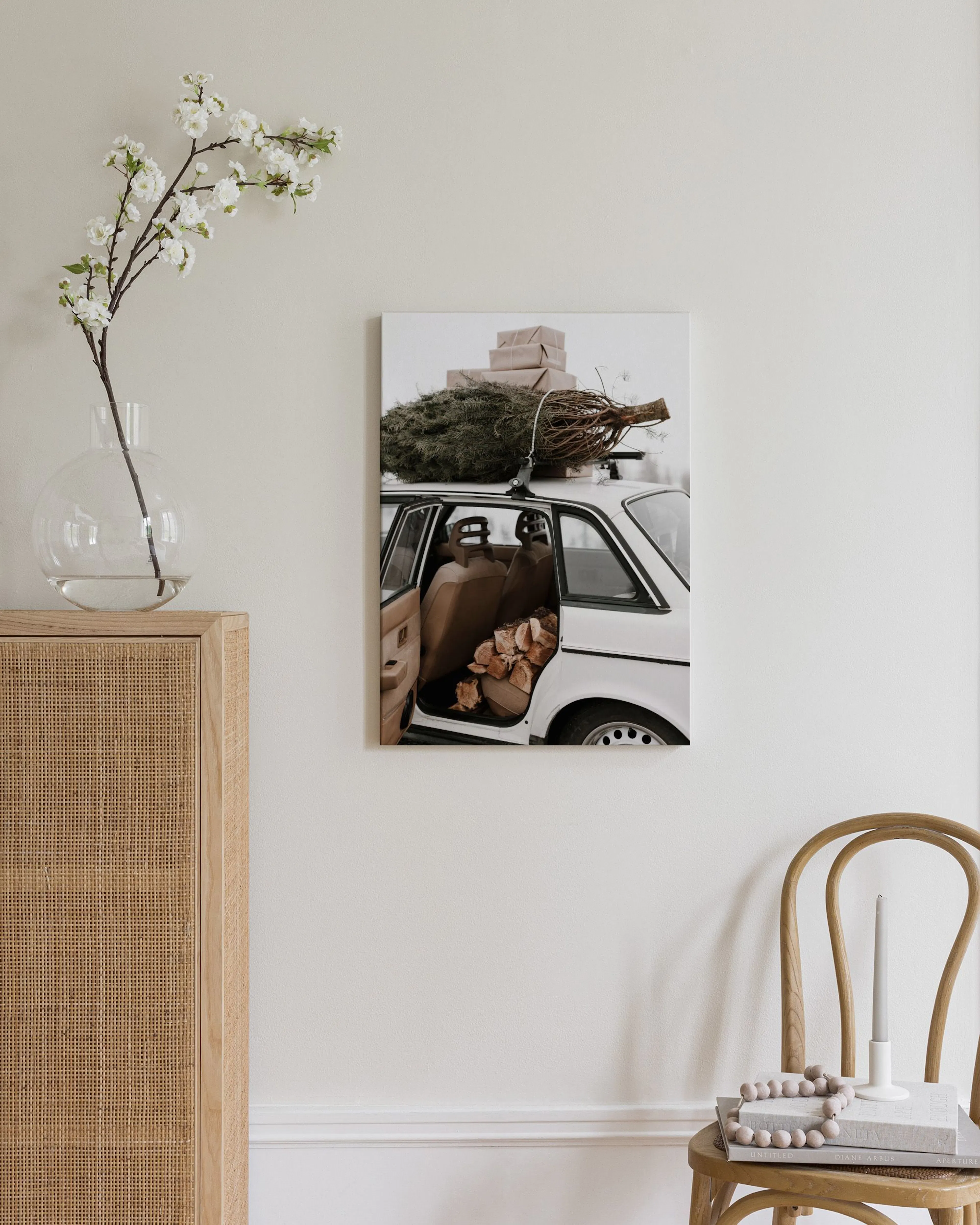 Canvas van een witte auto met kerstboom en cadeaus op het dak, en brandhout in de auto, hangend in een moderne woonkamer.