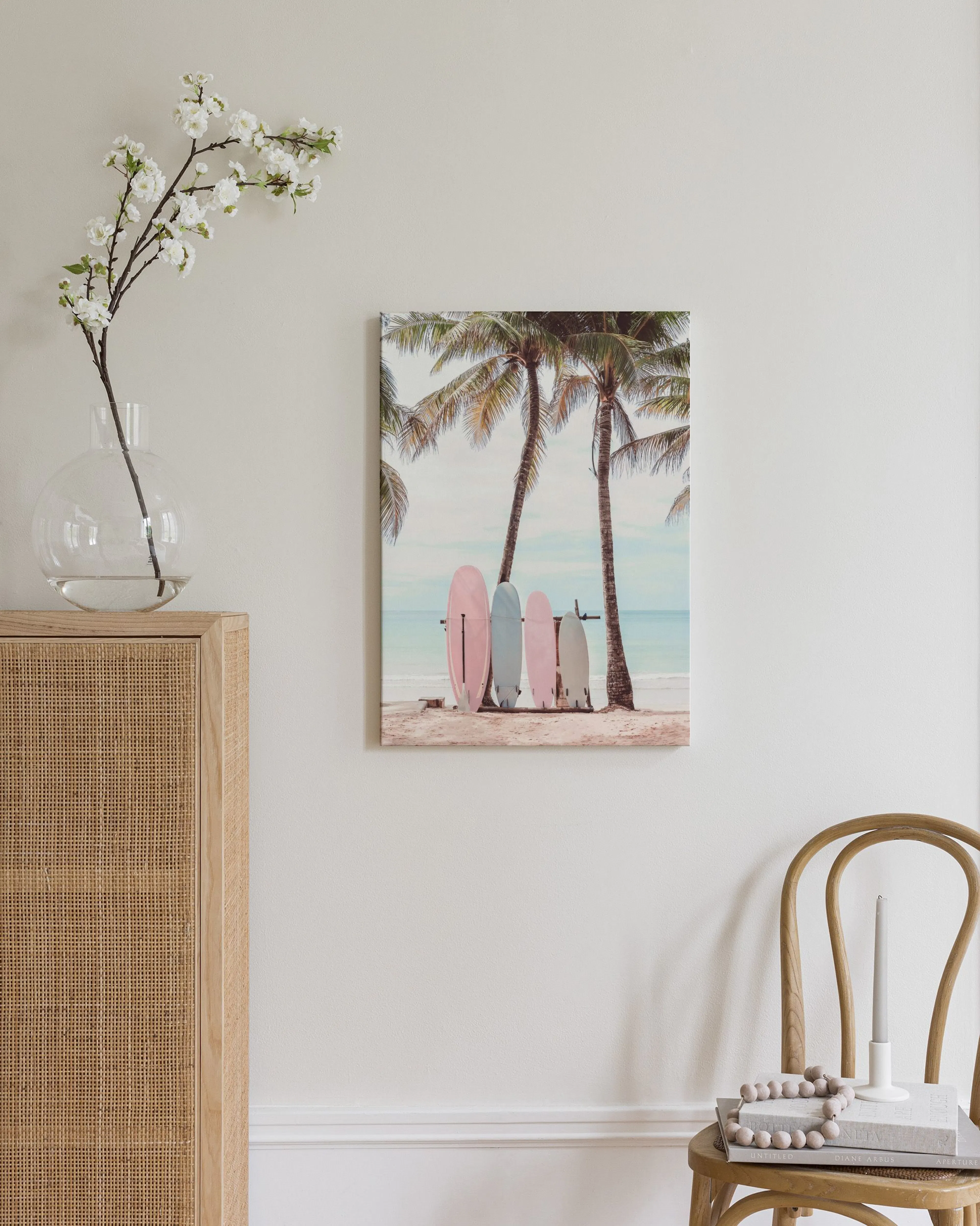 Toile murale de planches de surf roses et bleues sous des palmiers sur une plage, accrochée dans un salon moderne et lumineux.
