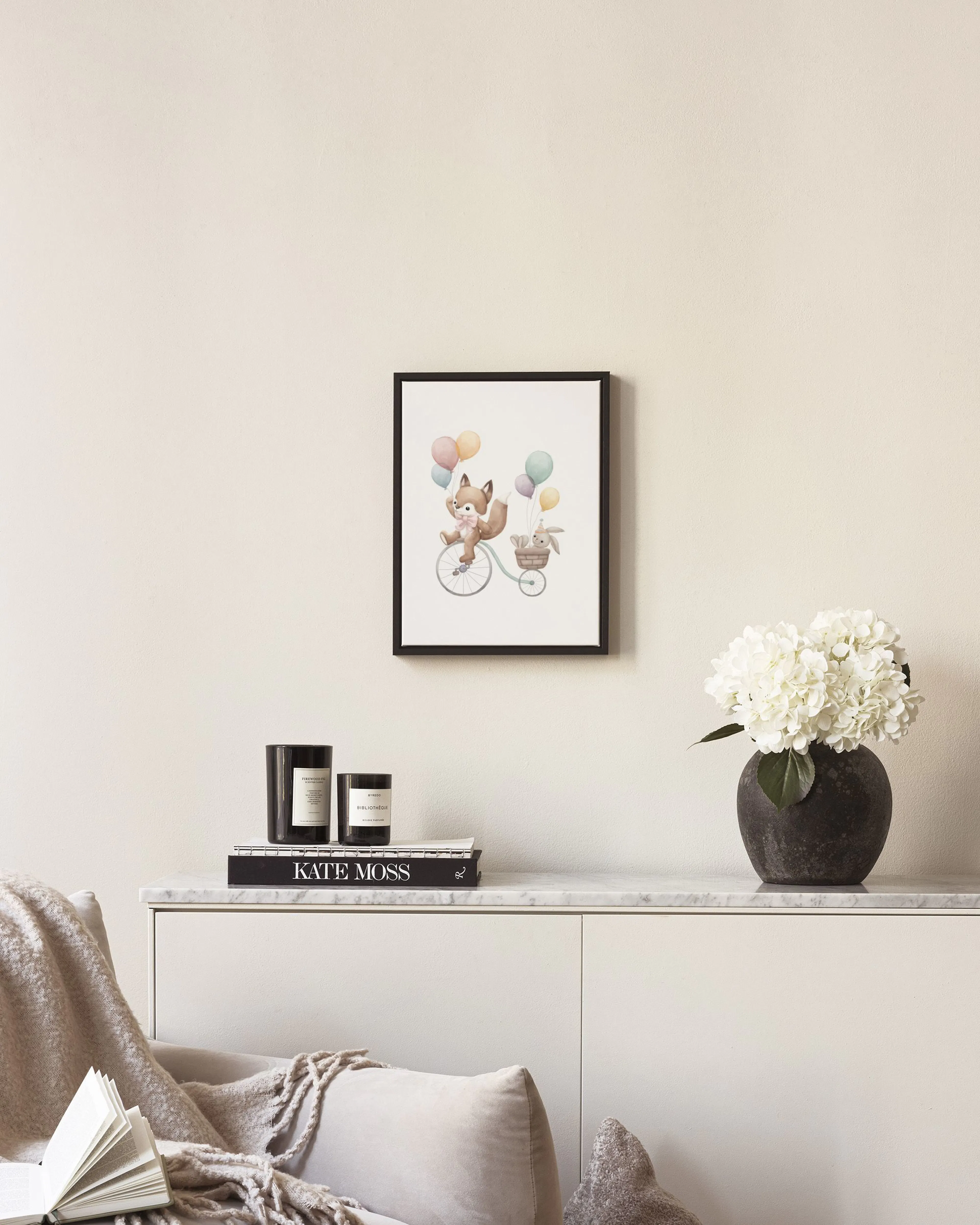 A canvas featuring a cute fox on a bicycle with balloons and a bunny in the basket, displayed in a neutral room.